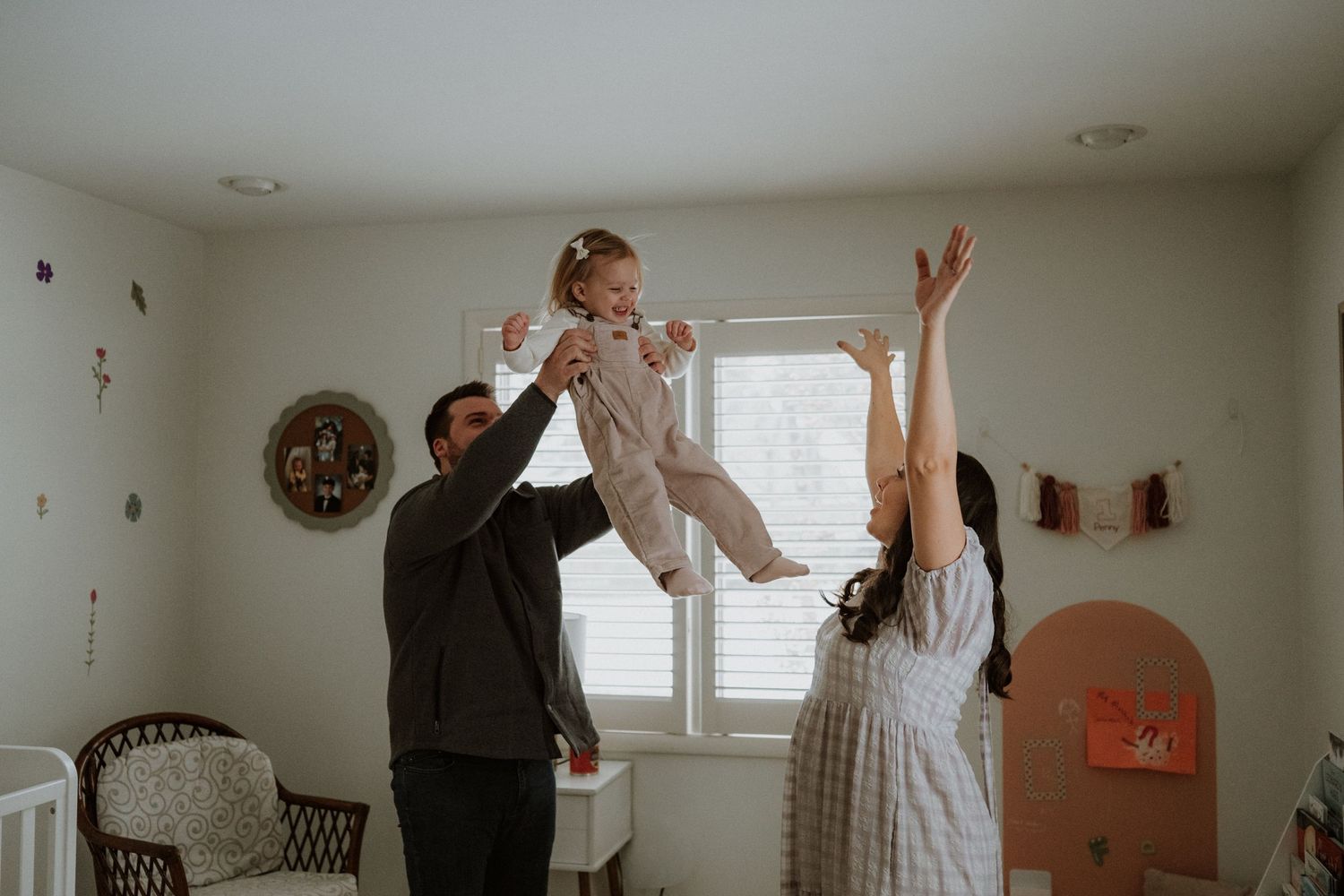 A playful family moment captured in a bright white room with natural lighting.