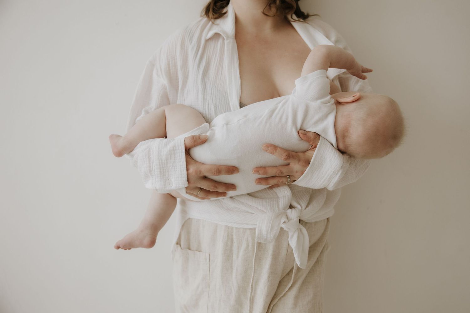 Delicate newborn photography session featuring soft white fabrics and natural light.