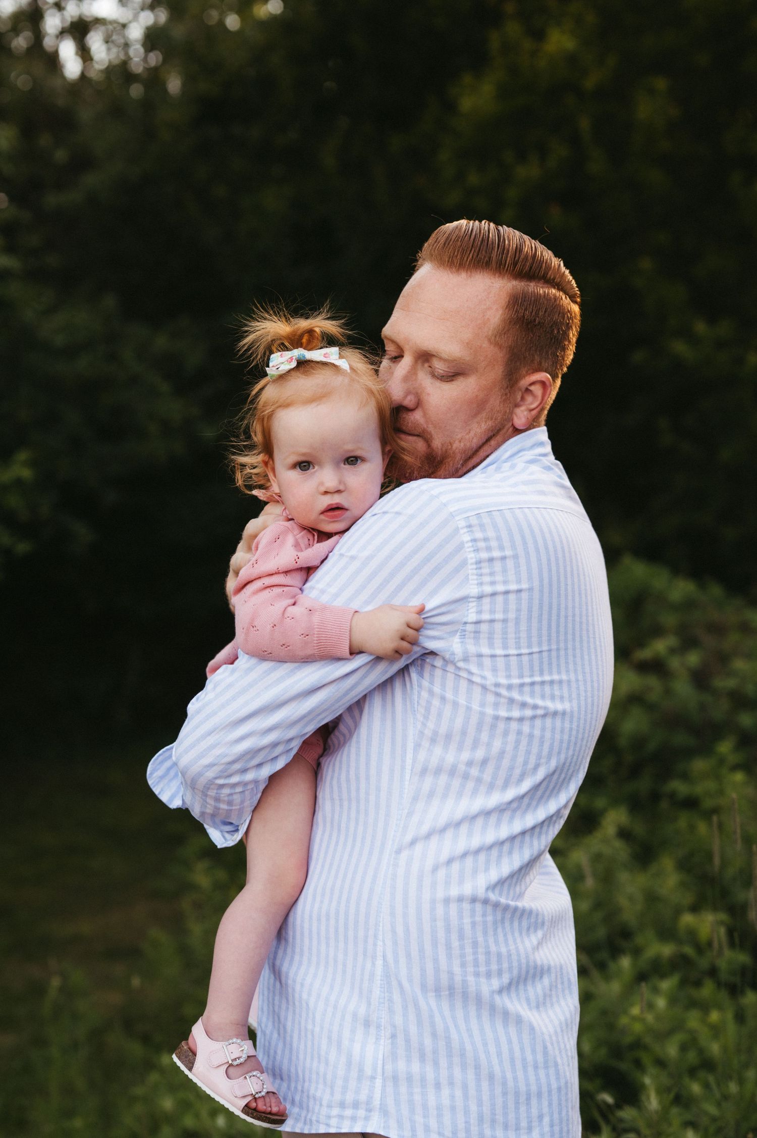 Sweet embrace between parent and child wearing coordinating white and pink outfits at sunset.