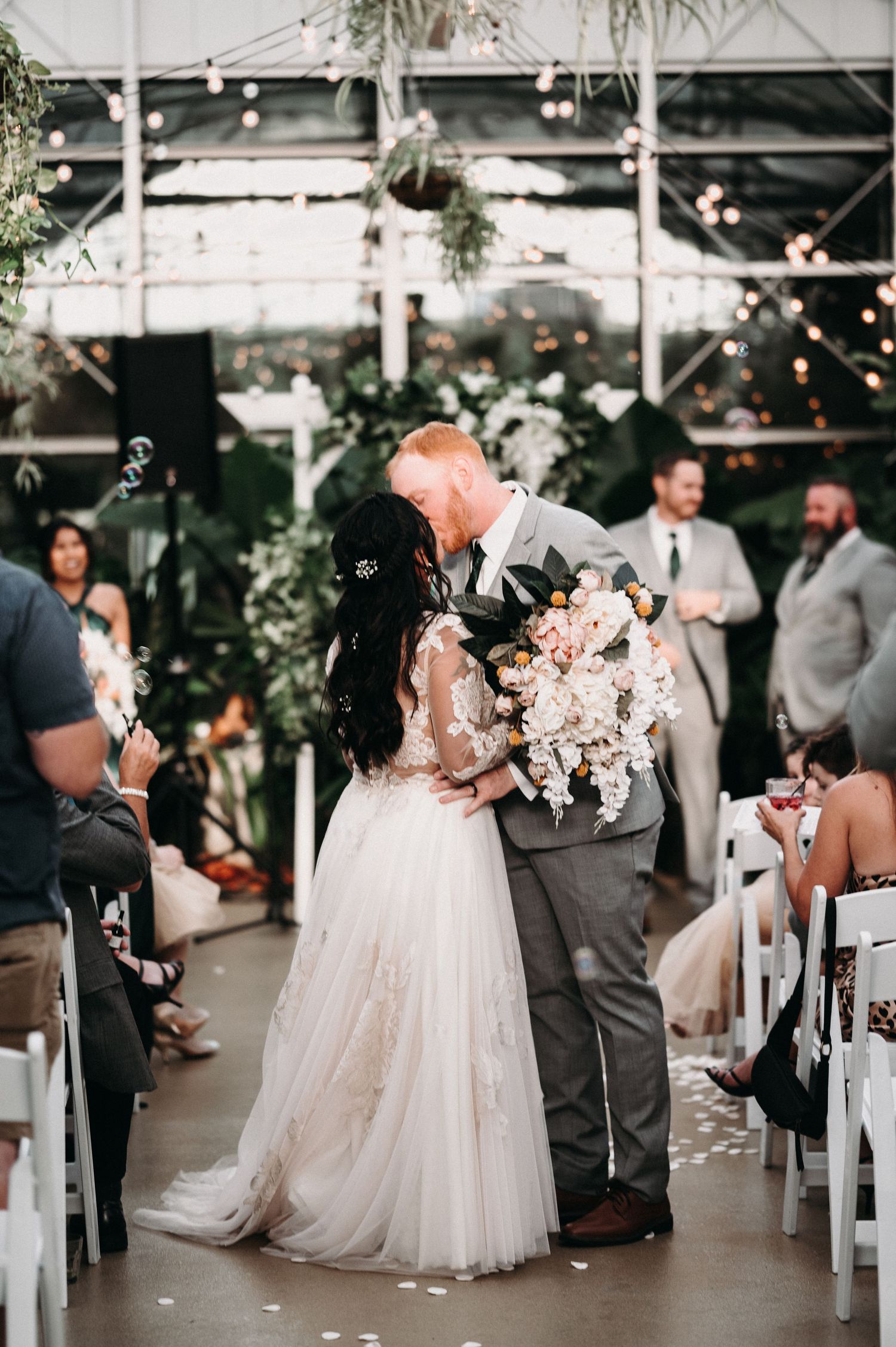 Intimate moment between newlyweds during recessional in greenhouse wedding venue.