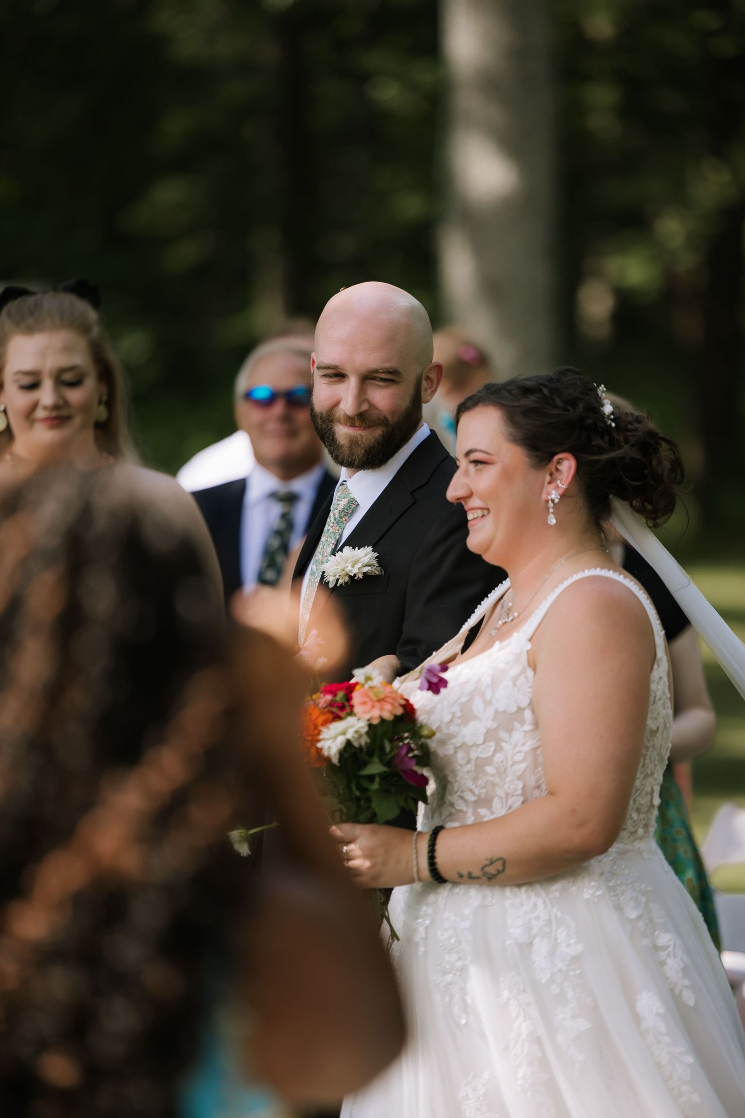 Couple shares a candid laughing moment during their outdoor wedding ceremony.