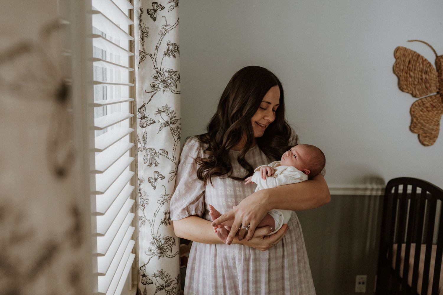 Intimate indoor family portrait with newborn baby by window with natural light.