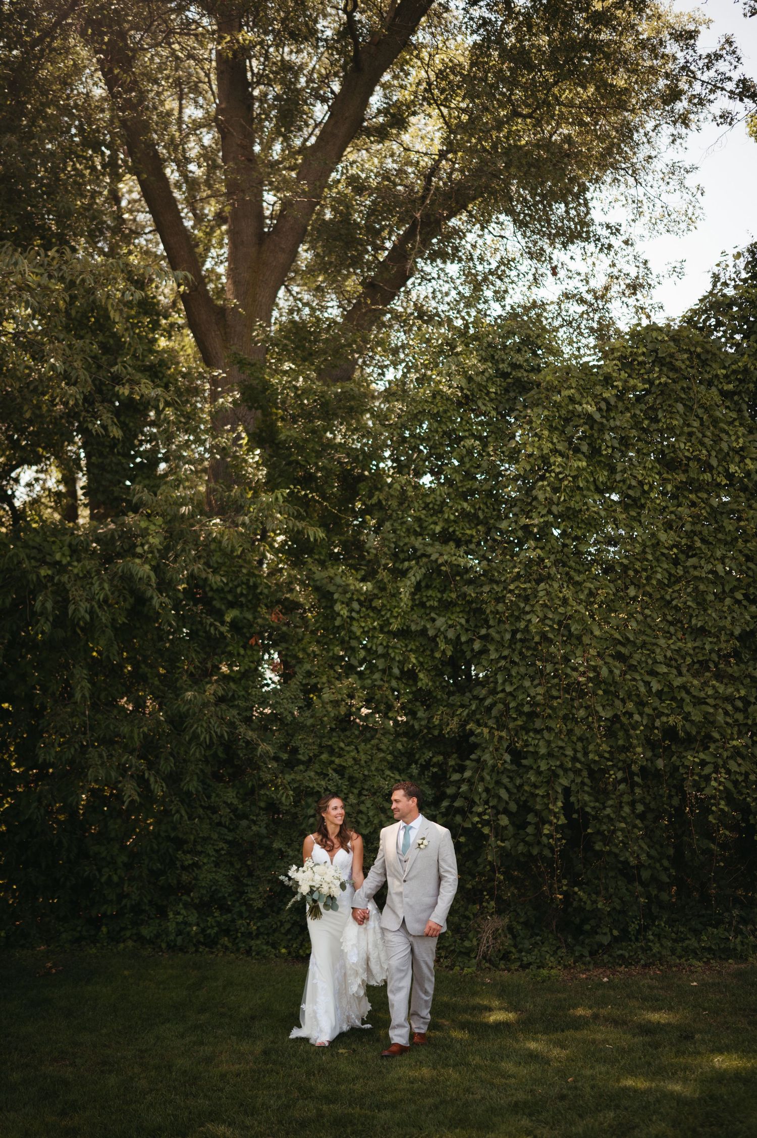 A wedding ceremony setup outdoors with lush green hedges and trees in the background.