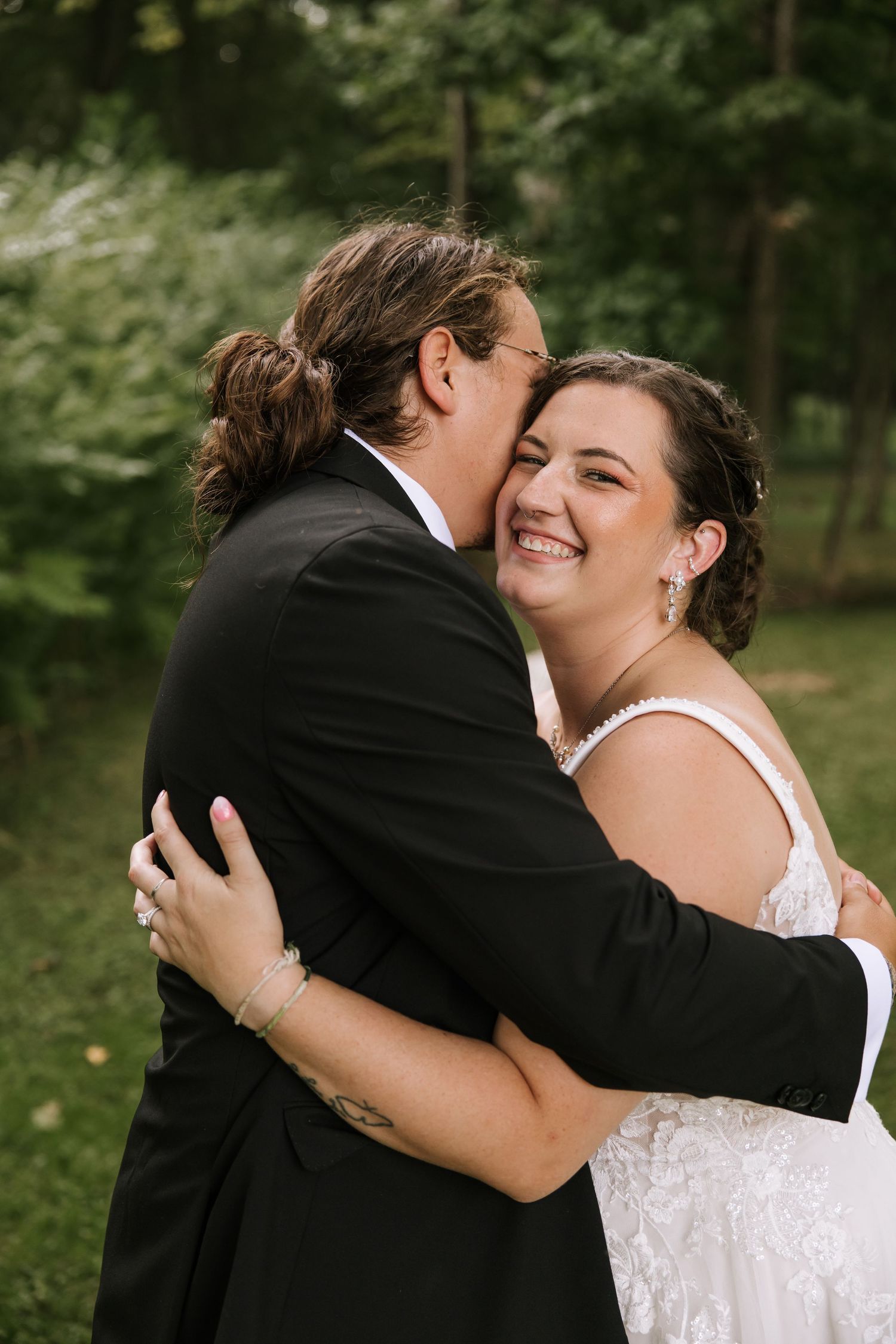 A couple shares intimate moments during their wedding photoshoot in a wooded setting.