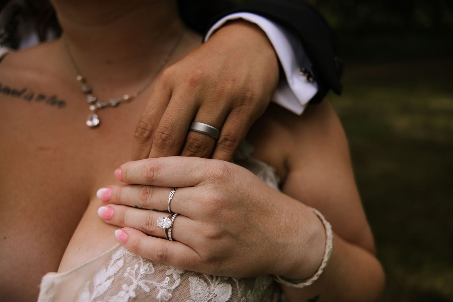 Close-up shot of hands wearing wedding rings with delicate jewelry details.
