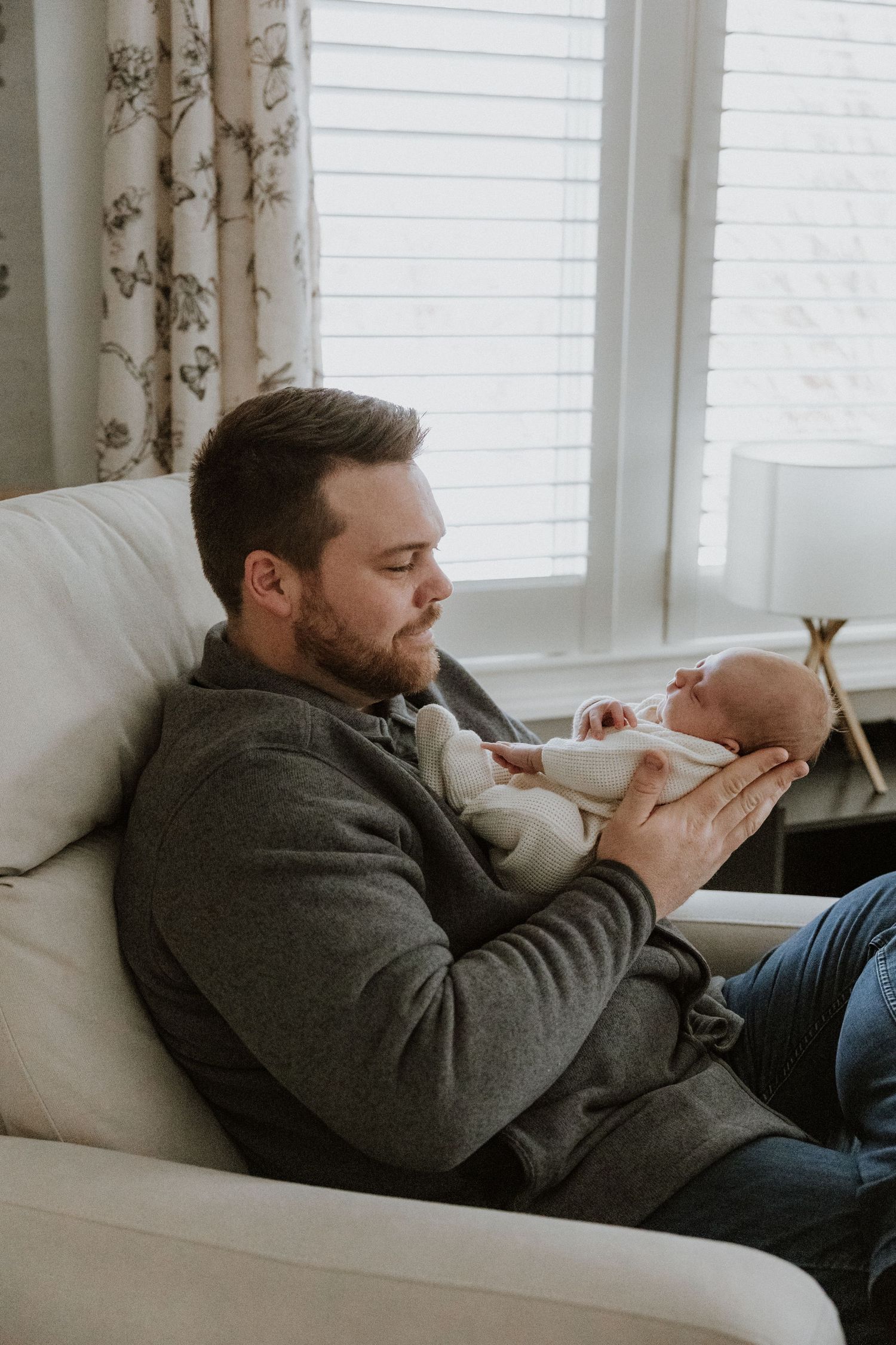 Relaxed moment on white couch with newborn baby in cozy living room setting.