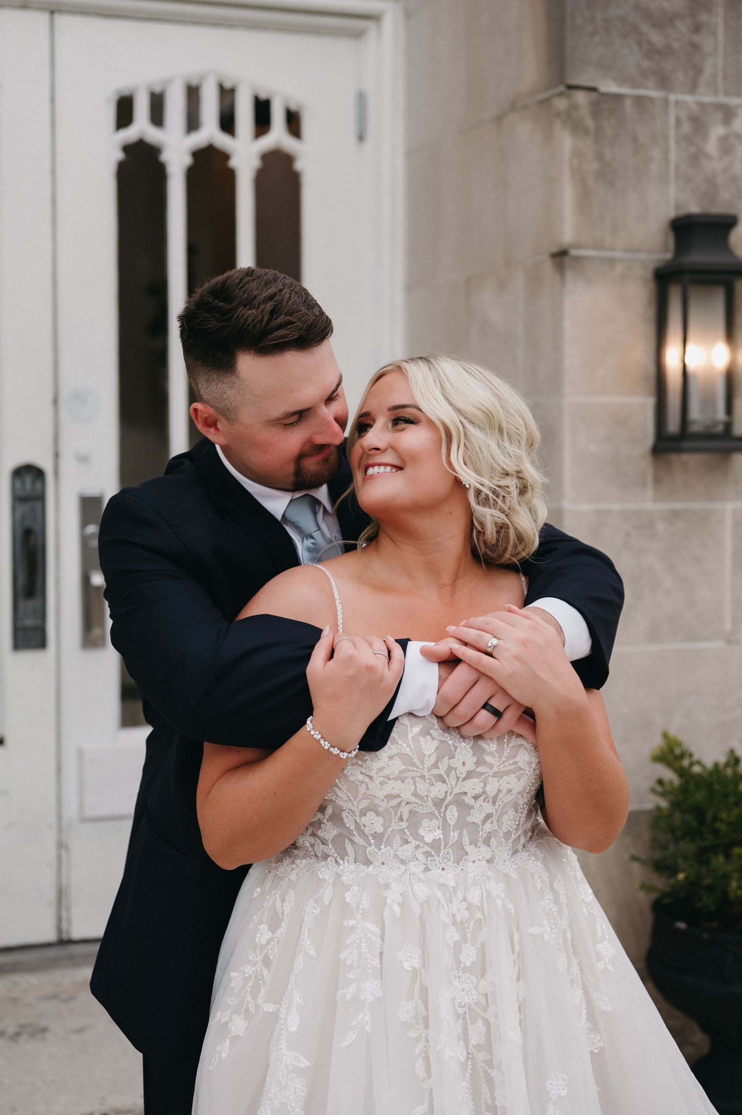 Romantic embrace of newlyweds in front of stone church entrance.