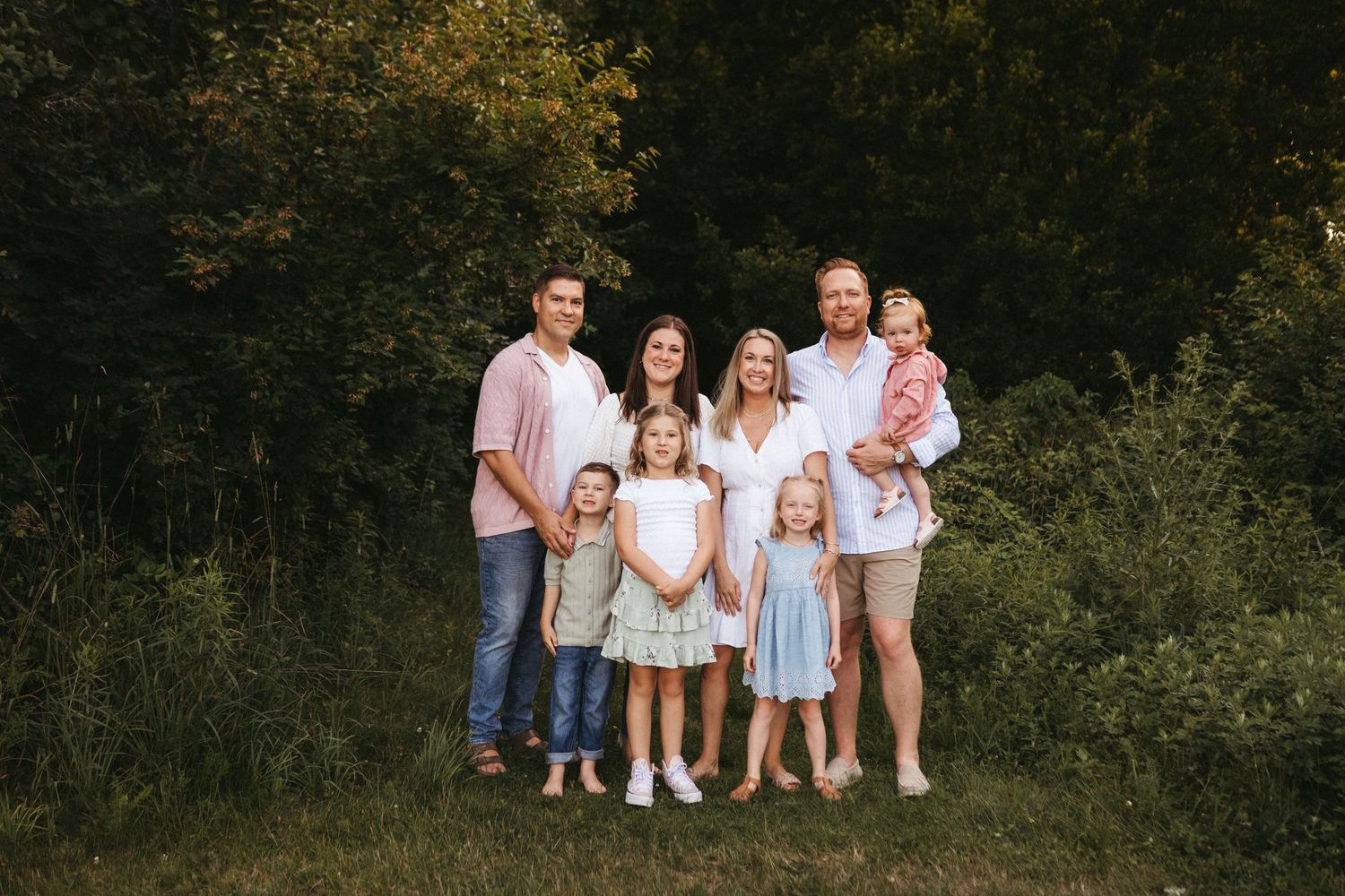 Group portrait session with coordinated white and neutral outfits in a natural setting.
