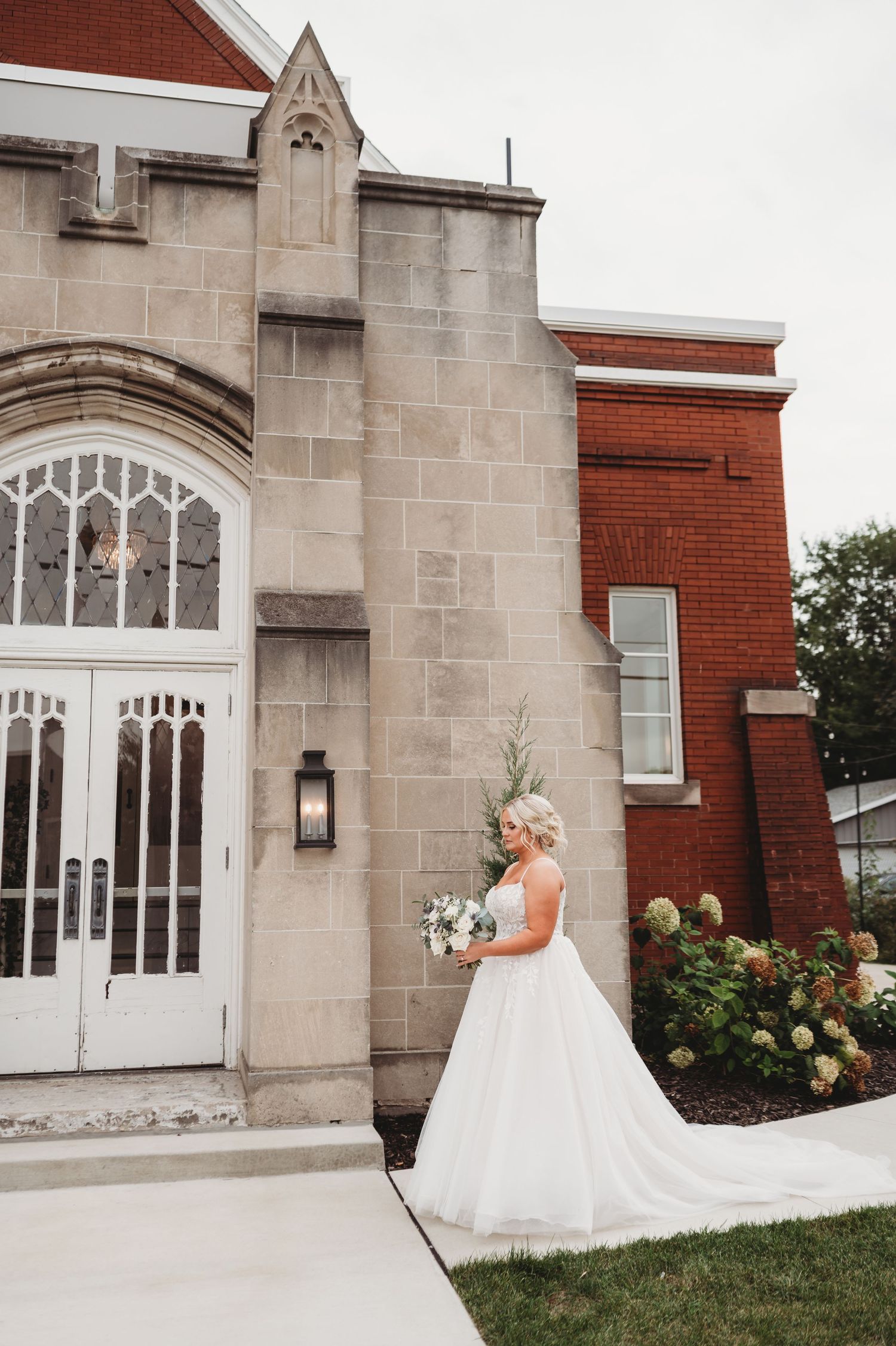A wedding dress silhouette against gothic church architecture with stone walls and ornate white doors.
