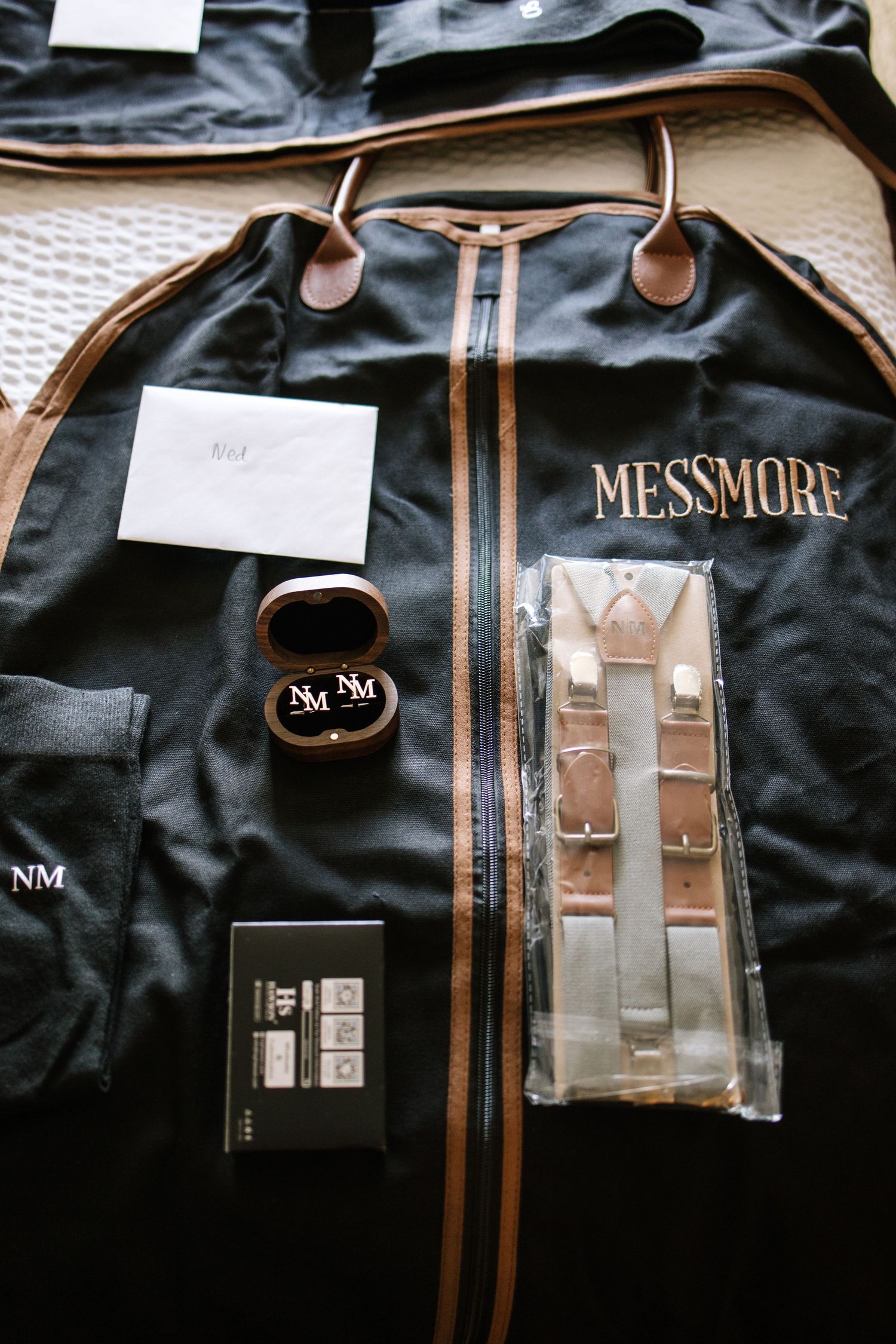 Collection of black leather bags and luggage with brand names and logos displayed against dark background.