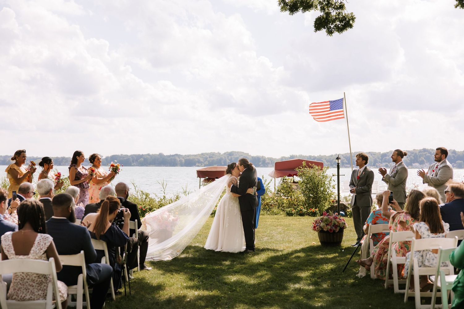 An outdoor wedding ceremony setup with white chairs and lakeside views under cloudy skies.
