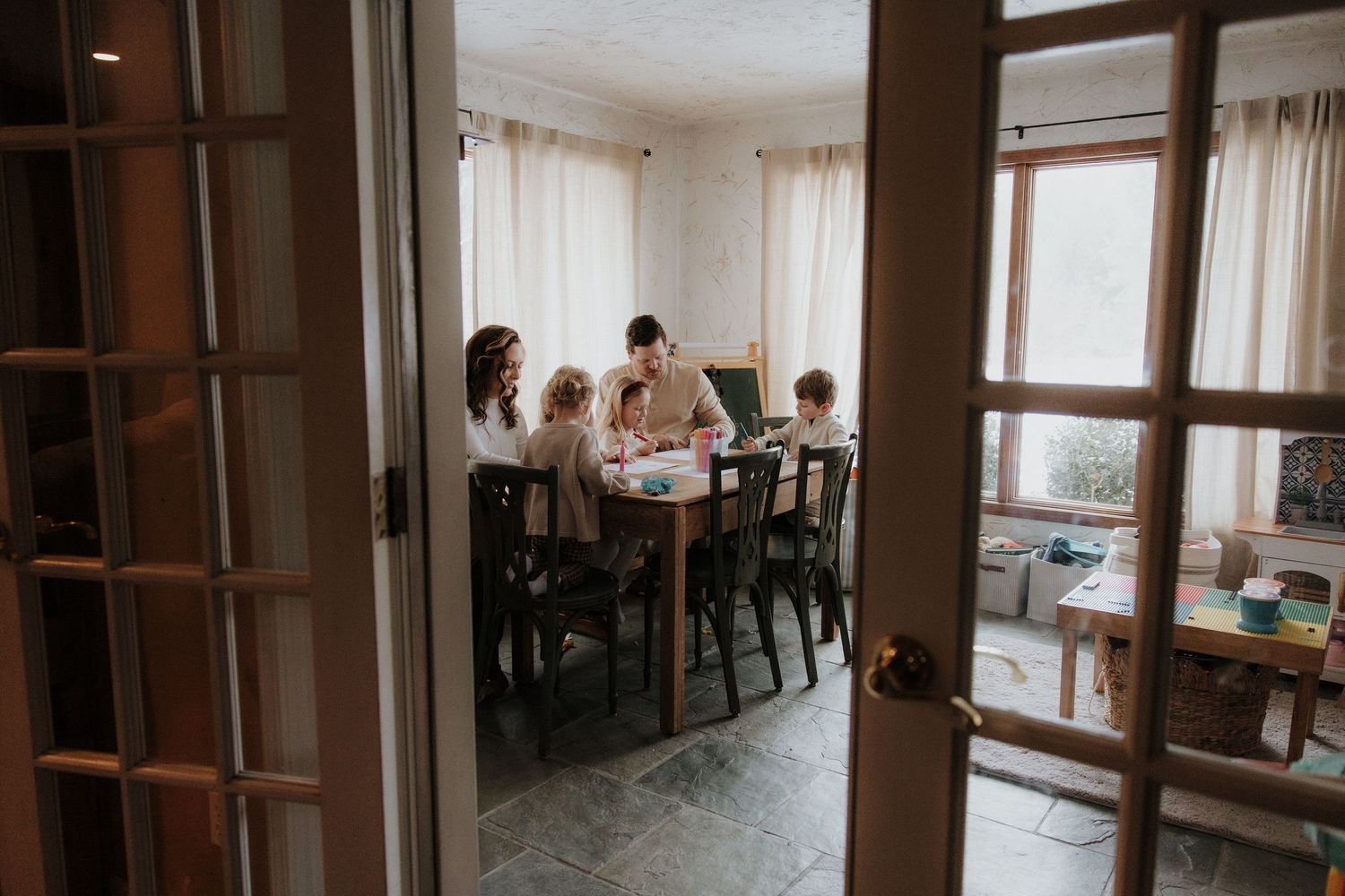 A family gathers around a dining table seen through an open doorway.