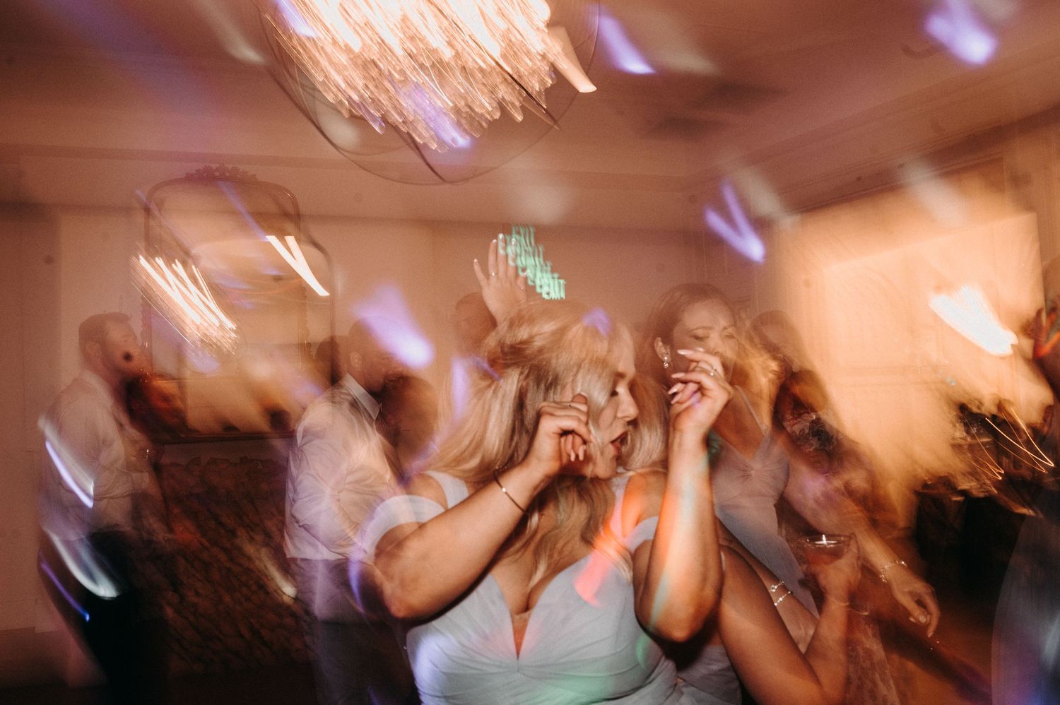Blurred motion shot of wedding reception dancing with colorful lights creating a dreamy atmosphere.