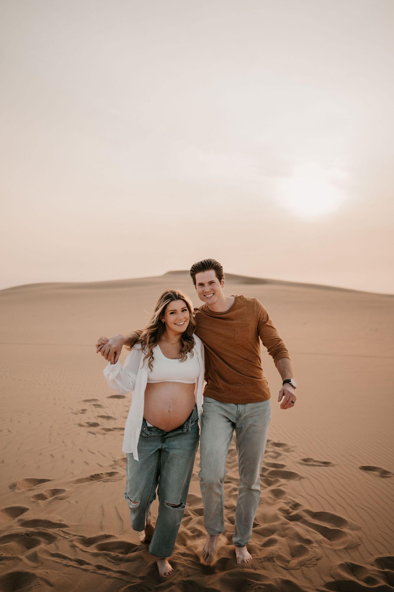 Joyful couple sharing intimate moment during desert maternity photoshoot.