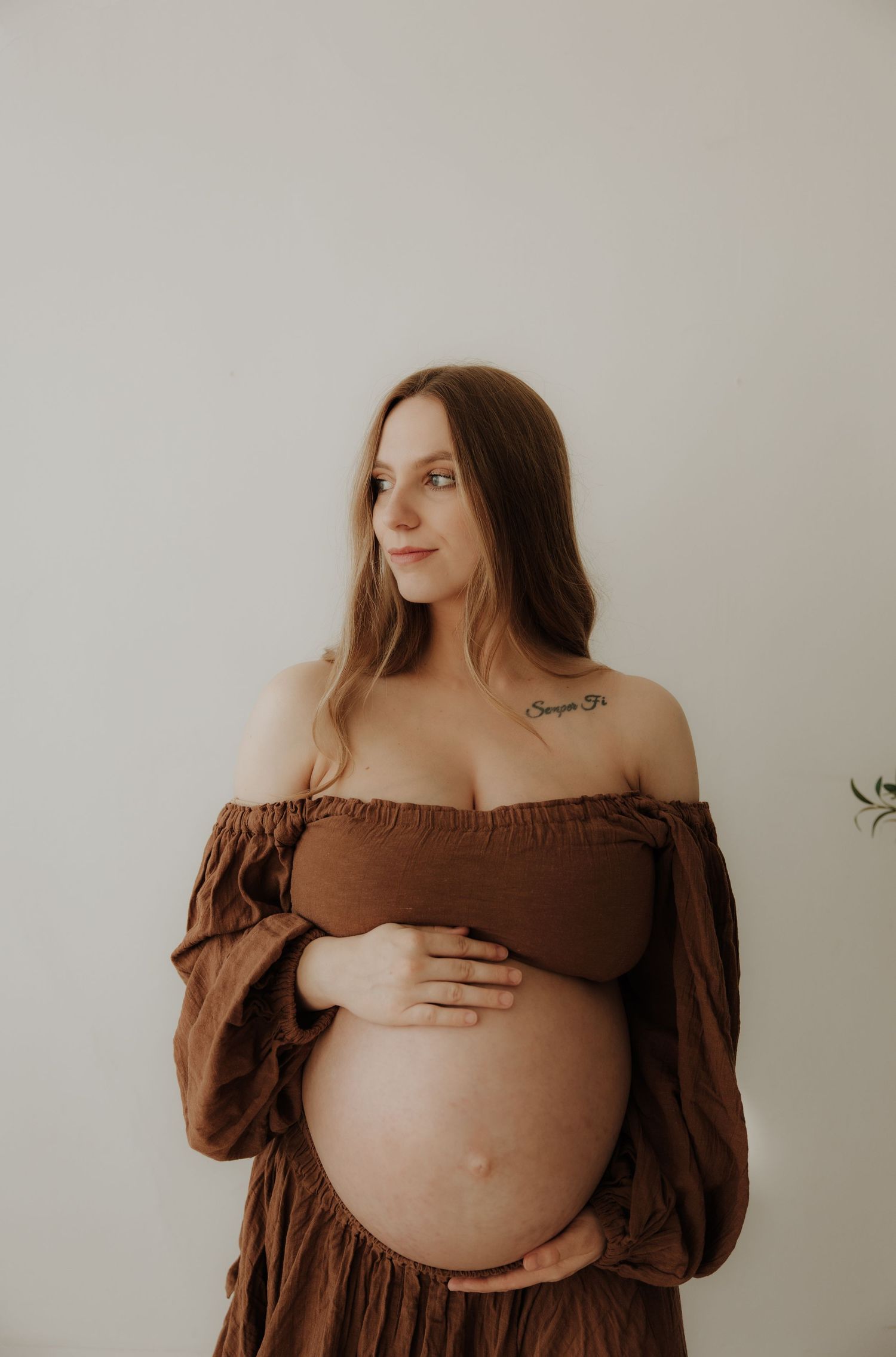 Artistic maternity portraits in brown off-shoulder dress with natural lighting.