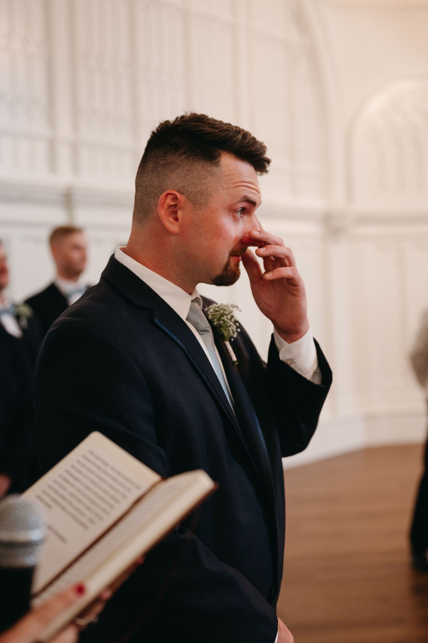 Emotional moment during wedding ceremony as groom wipes tears.