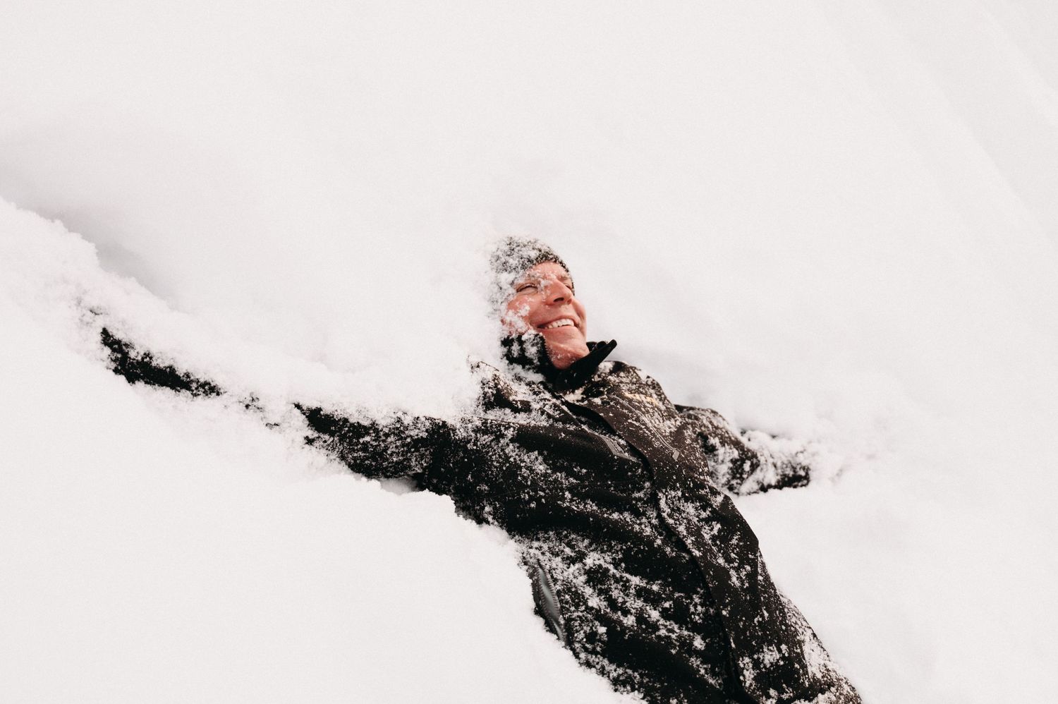 Figure making snow angel with dramatic pose in fresh powder snow.