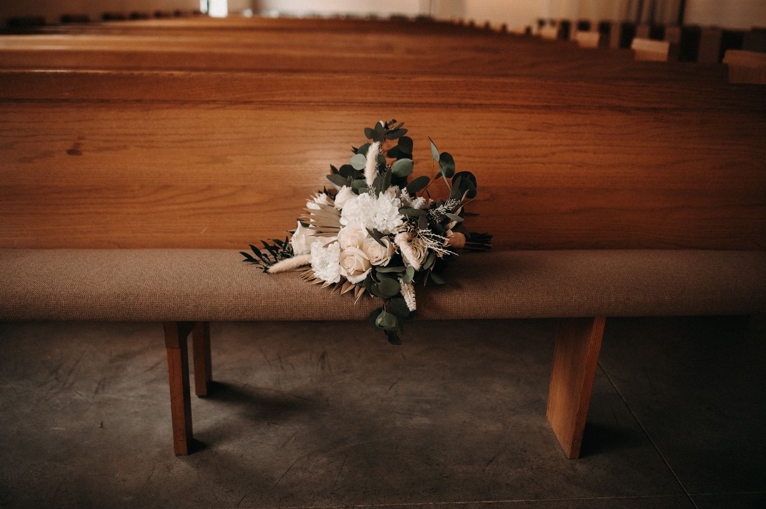 Wooden bench with delicate floral arrangements in warm lighting.