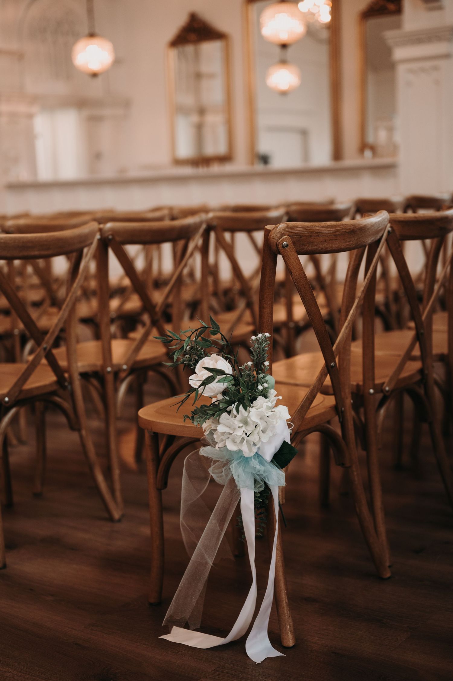 Close-up of wedding ceremony chair decorated with white flowers and ribbon in an elegant venue.