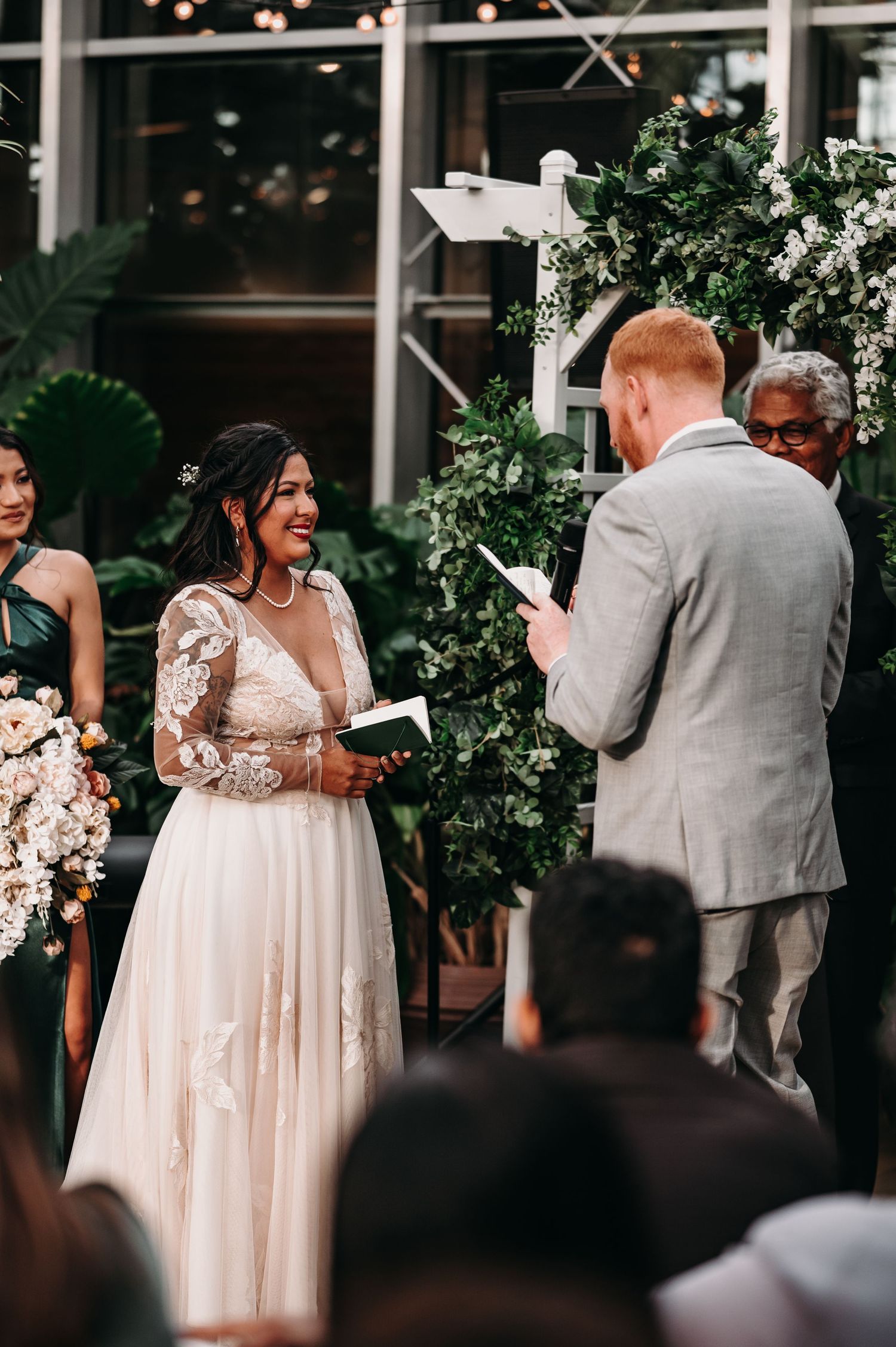 Couple exchanging personal vows during intimate greenhouse wedding ceremony.