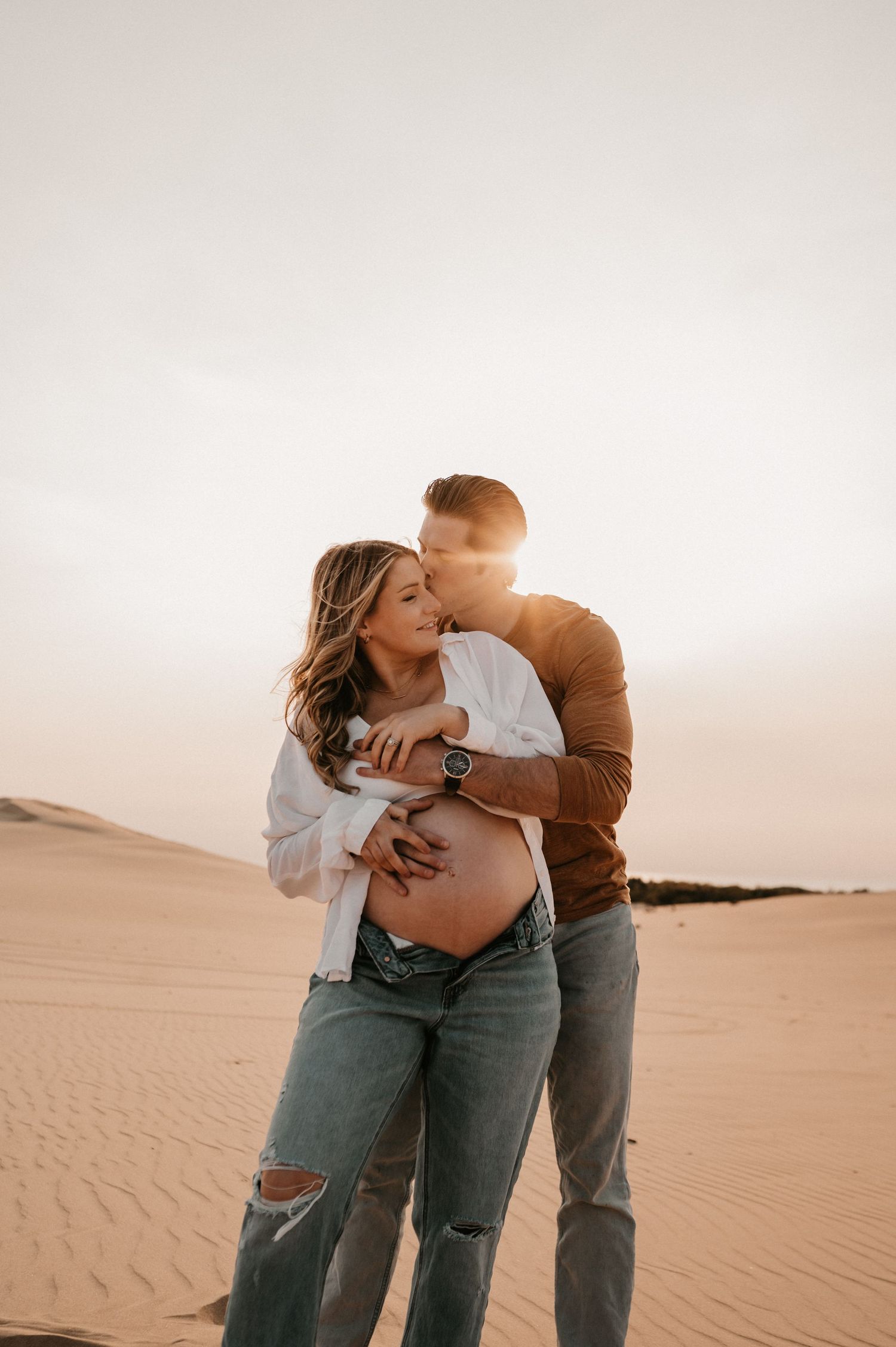 An intimate maternity photo captured in the desert during golden hour.