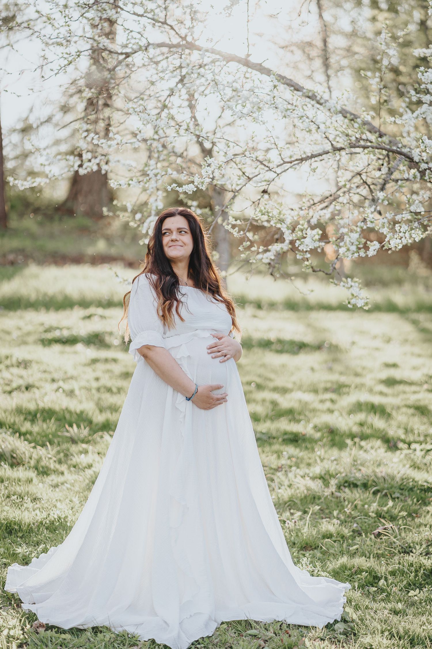 Gravidfotografering i vårmiljö med blommande träd i bakgrunden