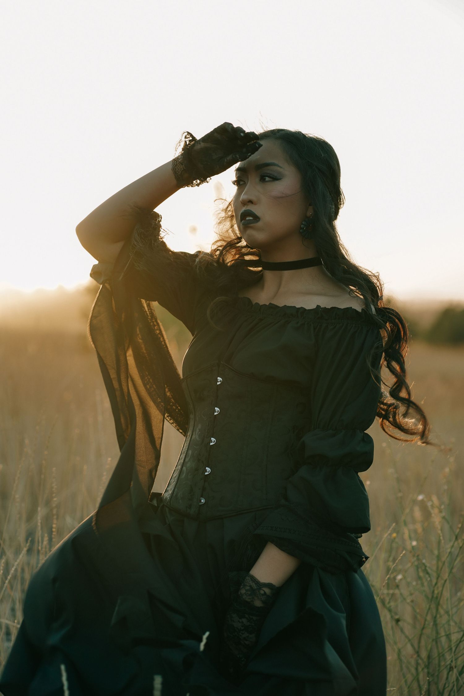 Artistic fashion portrait in a field during sunset with dramatic lighting and poses.