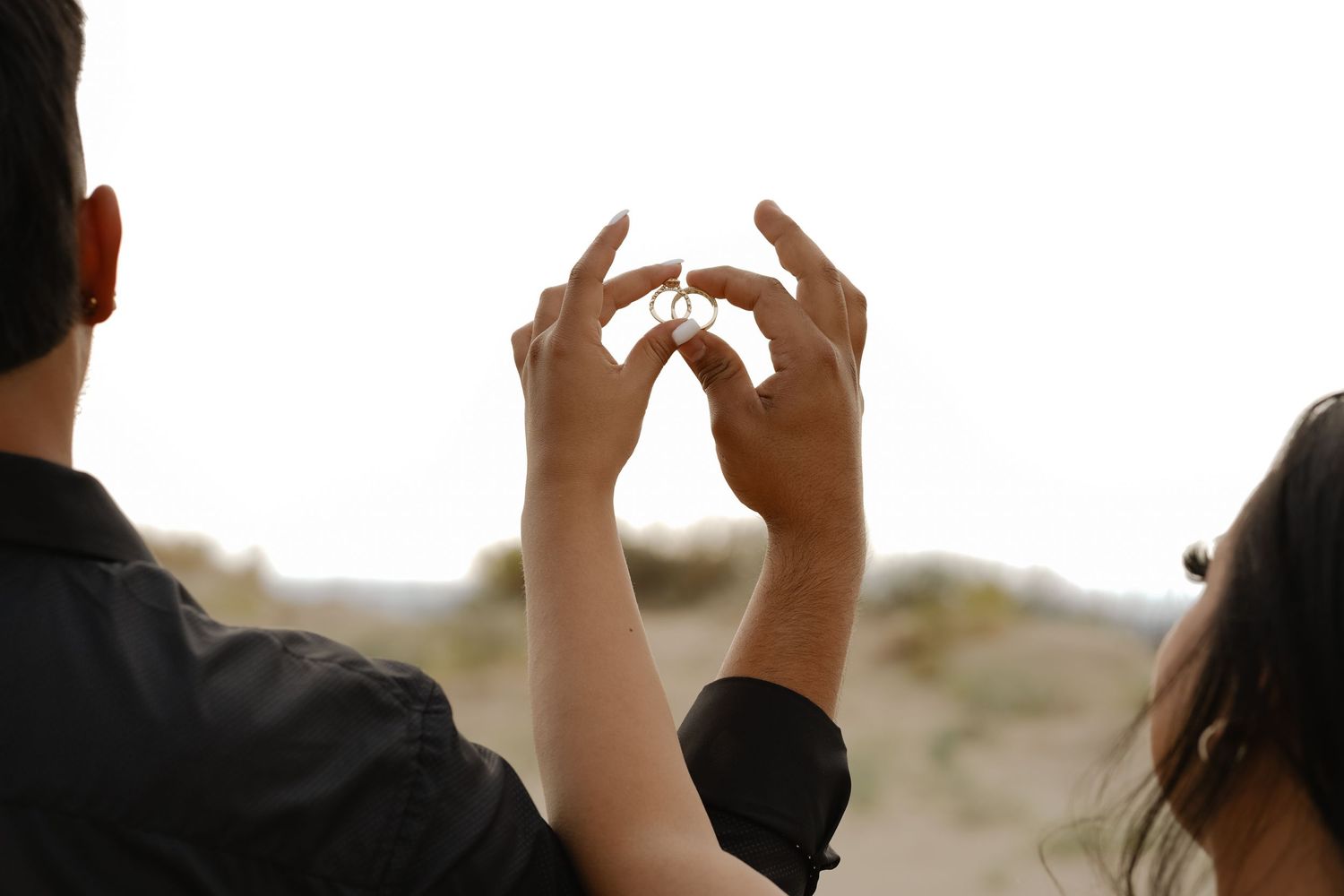 Silhouetted hands forming a heart shape against a bright sky.
