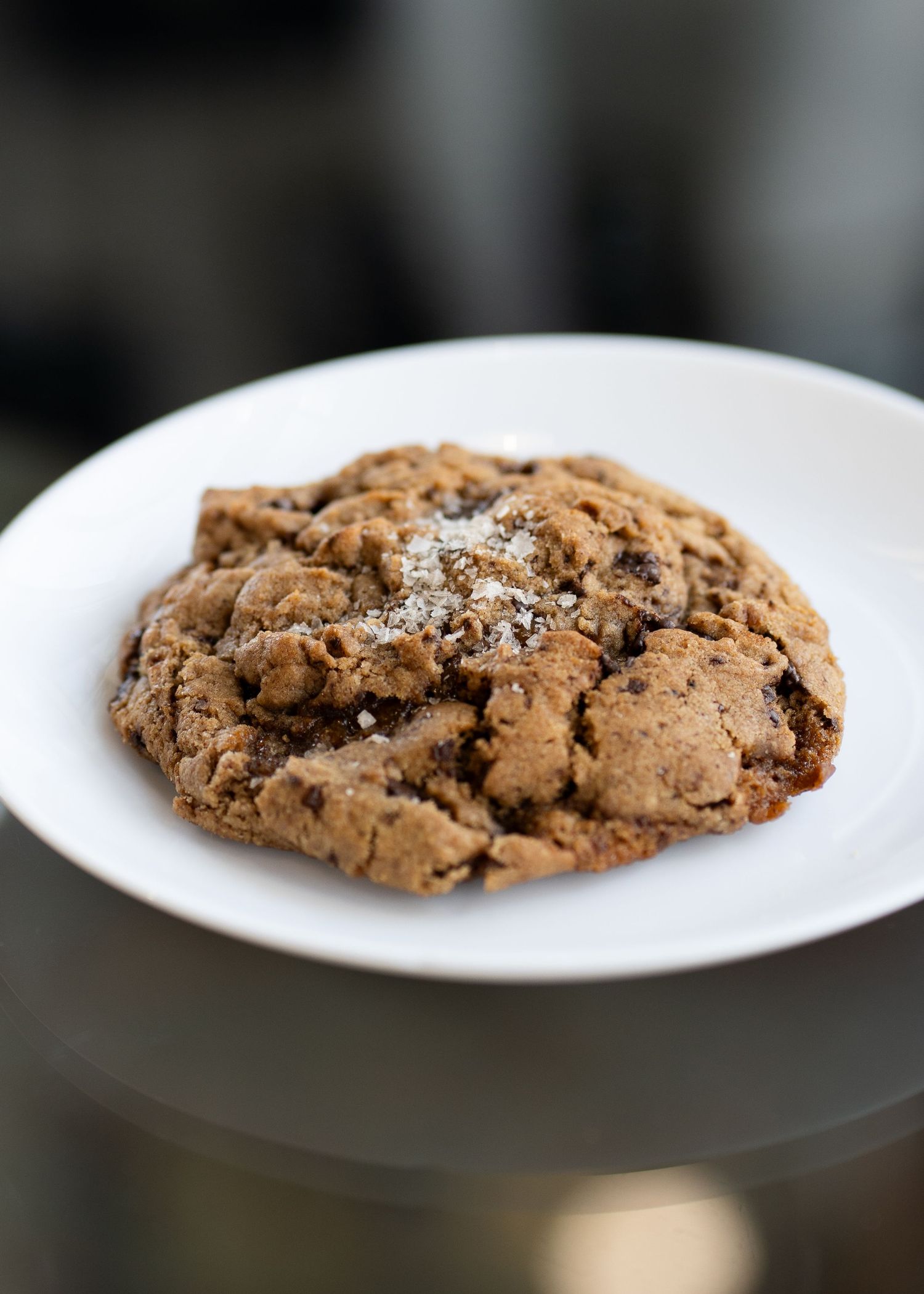 Chocolate chip cookie on a white plate shown from multiple angles.