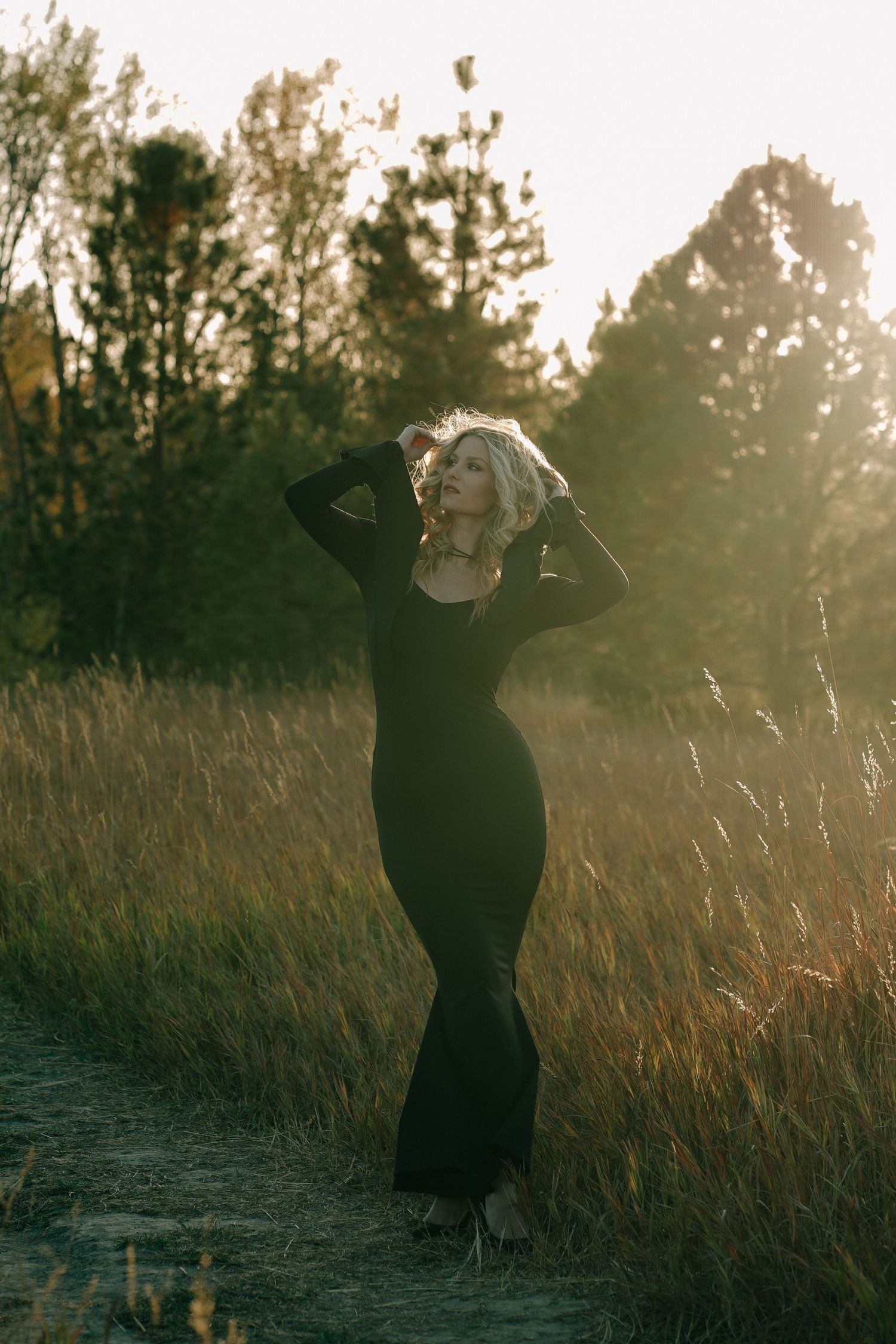 Silhouette figures dancing in a field during golden hour with tall grass and trees.