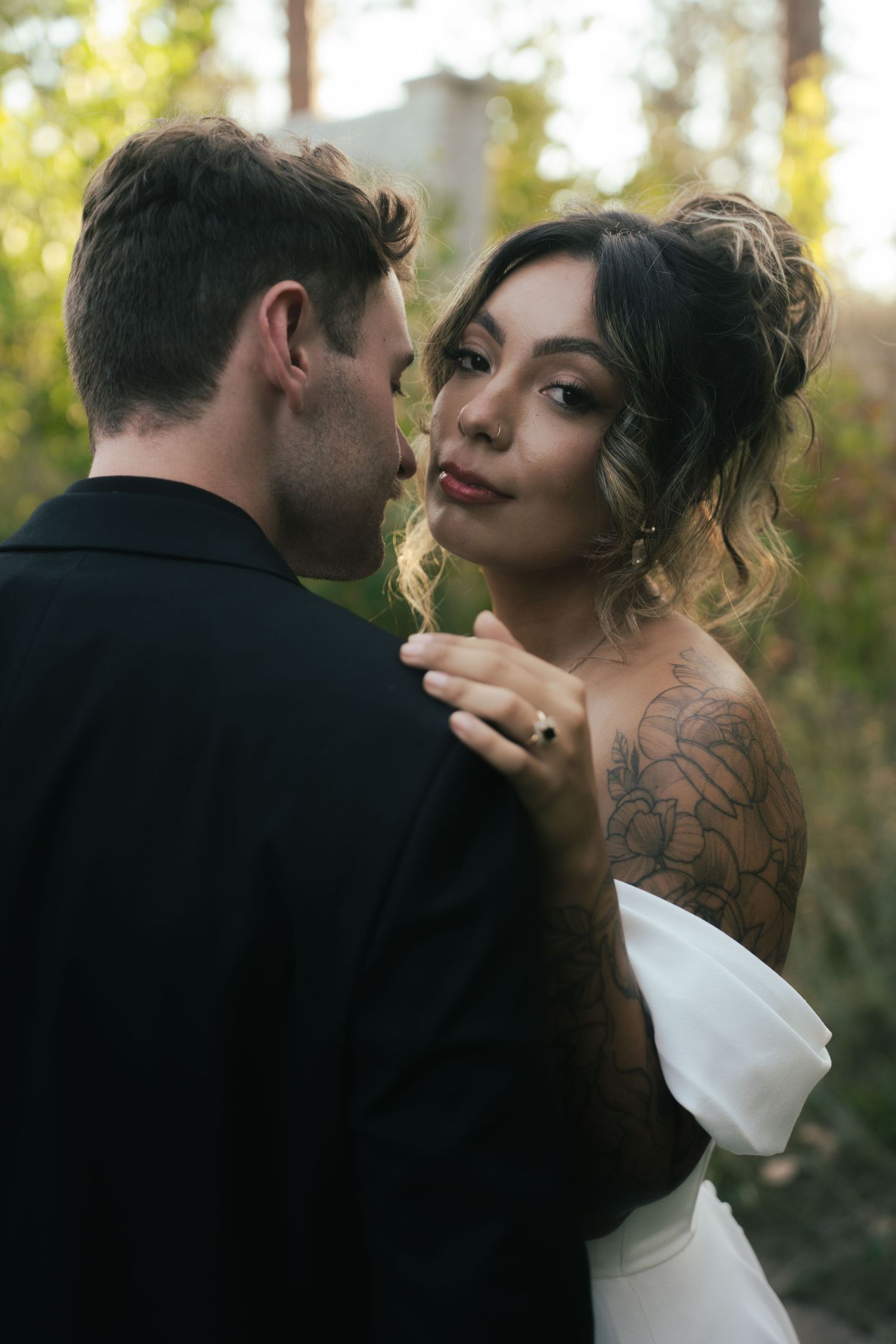 Intimate wedding couple moment captured in golden outdoor lighting with bride in white dress.