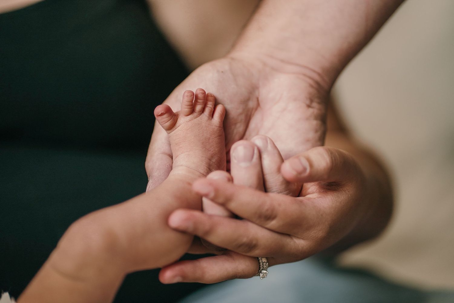 Close-up series of gentle hands touching and caressing a sleeping newborn baby on white blanket.