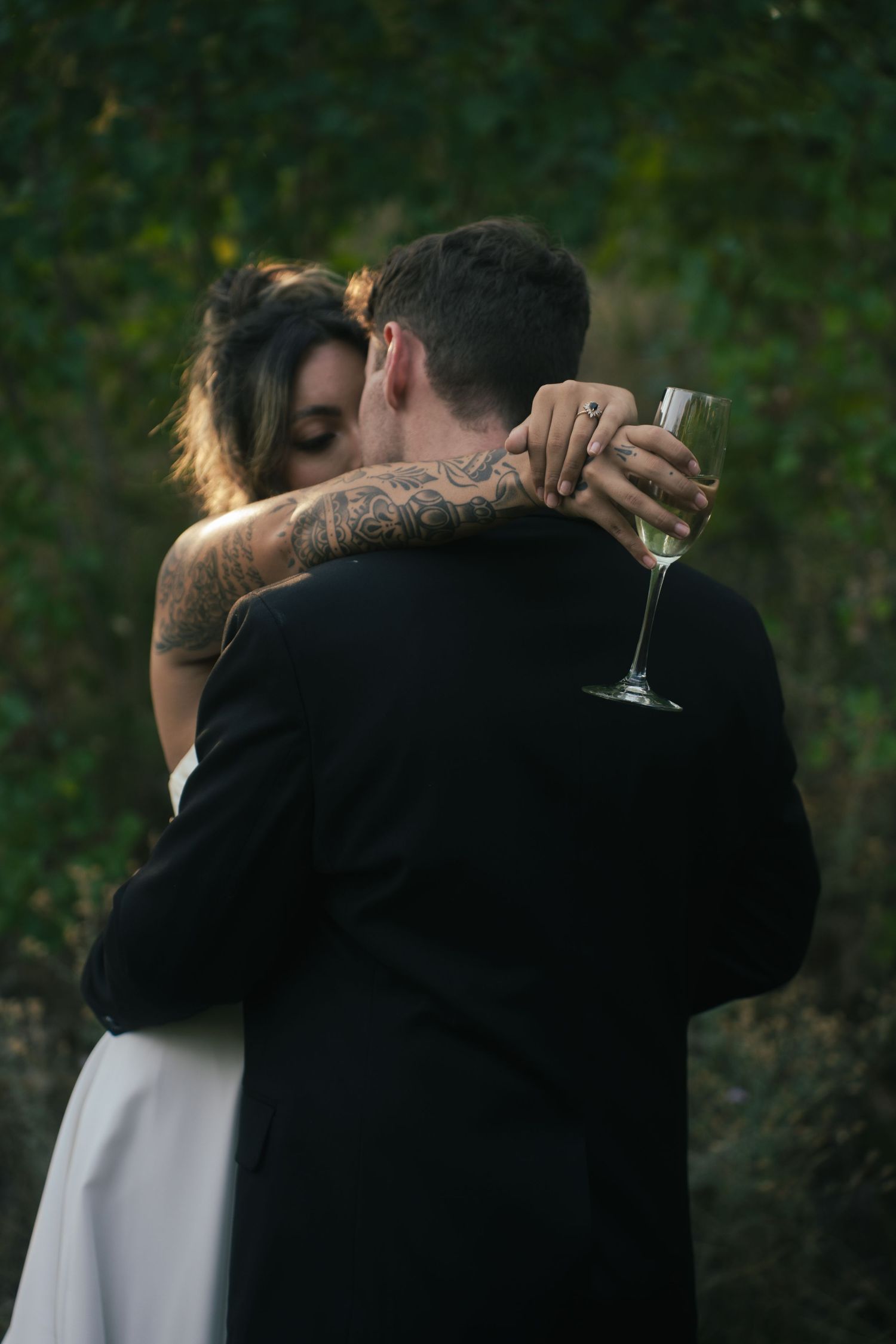 Tender embrace between newlyweds in an outdoor garden setting at sunset.