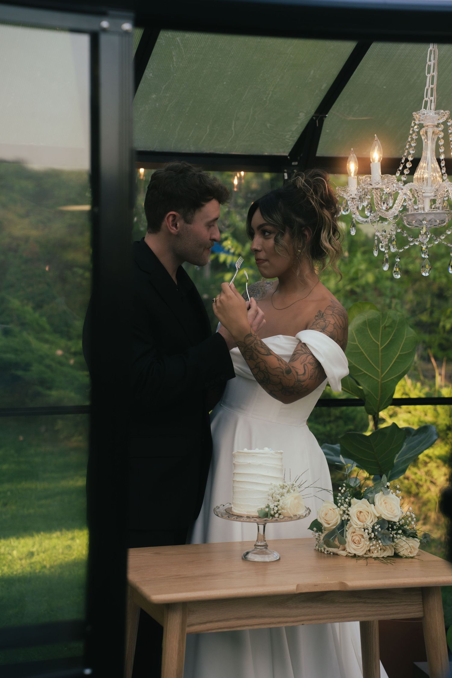 Romantic indoor wedding scene with chandelier lighting and white floral decorations.