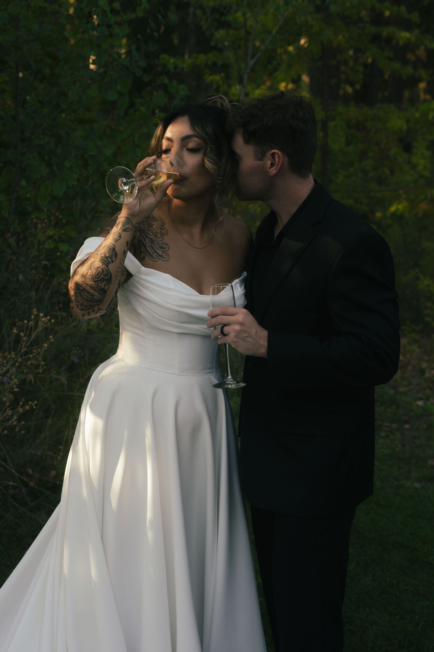 Elegant couple shares intimate moment in garden setting with flowing white wedding dress.