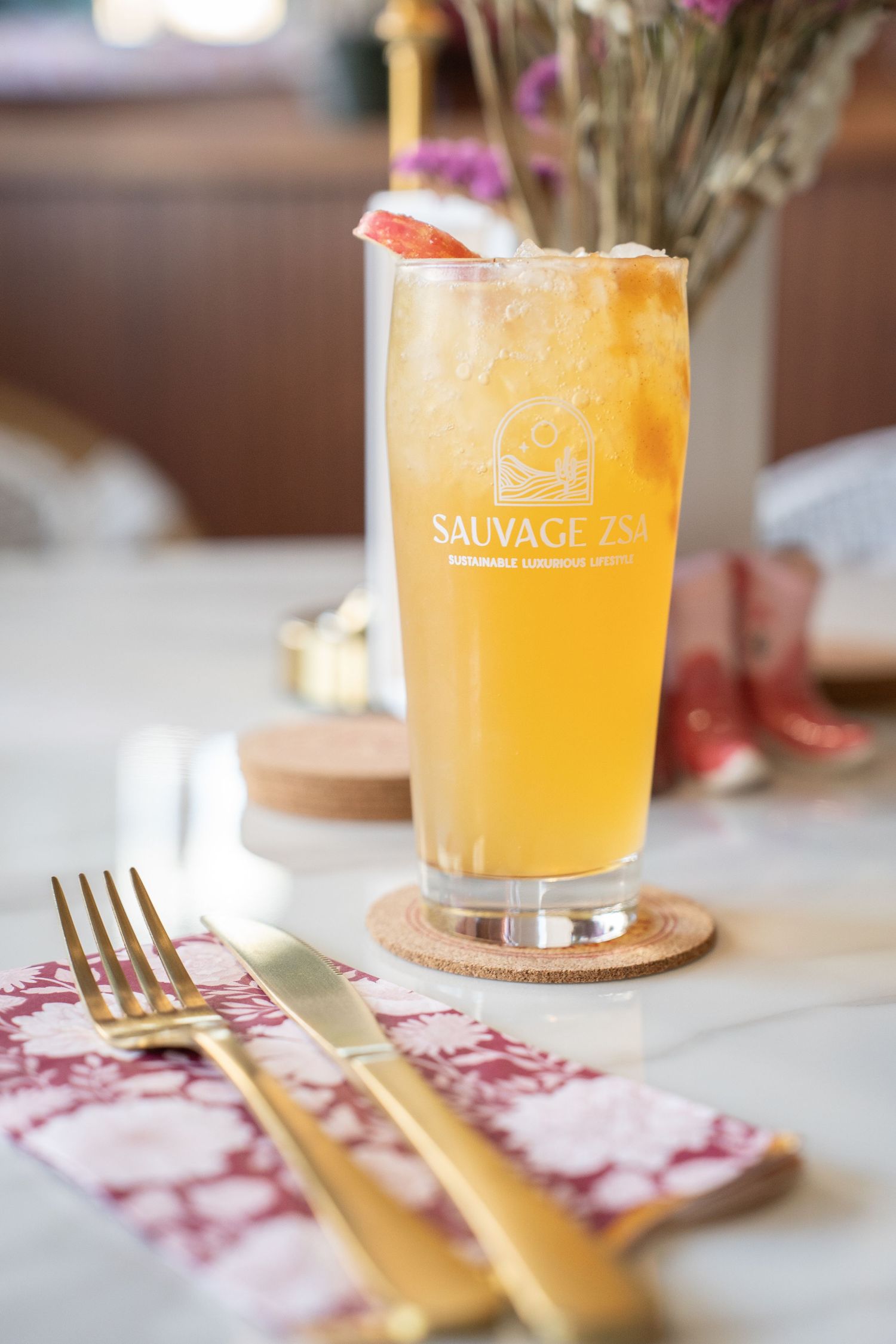 Orange cocktails with gold utensils on a white tablecloth at an upscale restaurant.