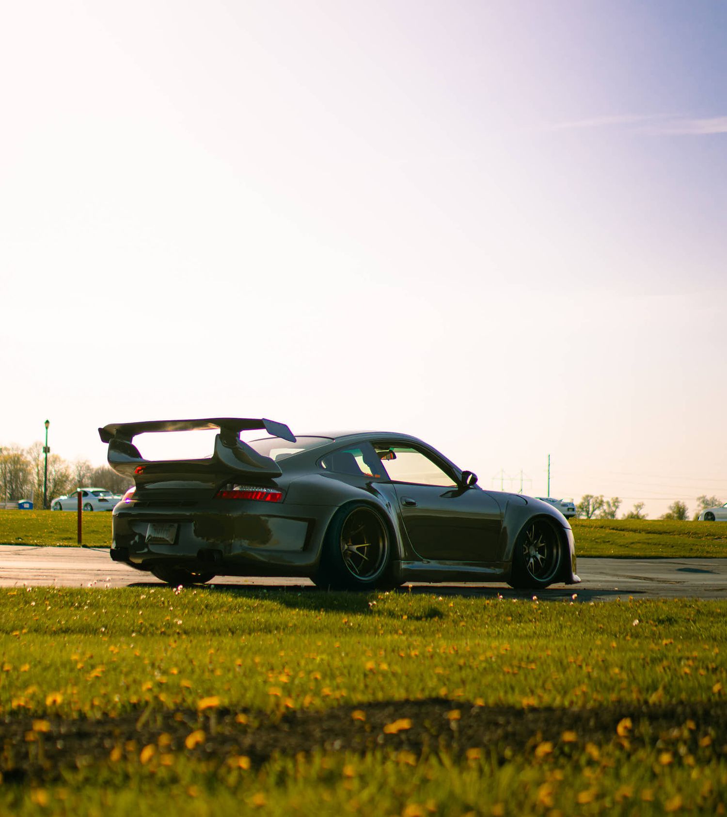 Green Porsche 911 GT3 RS widebody sports car parked on a sunny day with green grass and a bright sky backdrop during WCEC season opener!