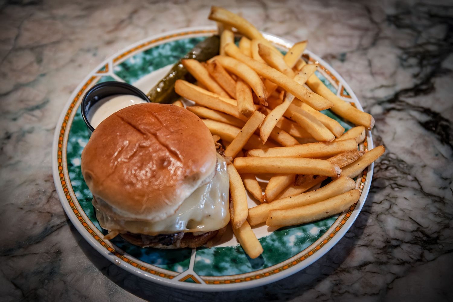 Classic cheeseburger with melted cheese served with golden crispy fries on a decorative plateat Estelle's Eatery.