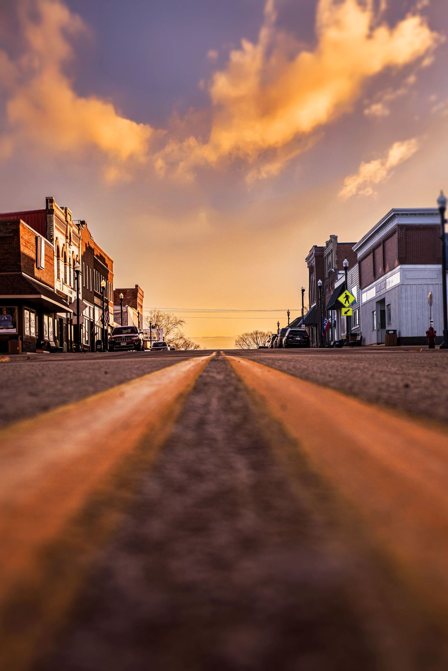 Low angle view of a small town main street at sunset with golden clouds overhead.