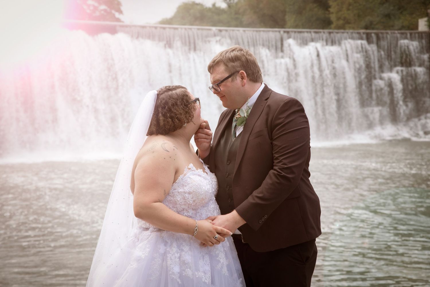 Bride and groom sharing a romantic moment in front of a beautiful waterfall outdoors in Lanesboro MN.