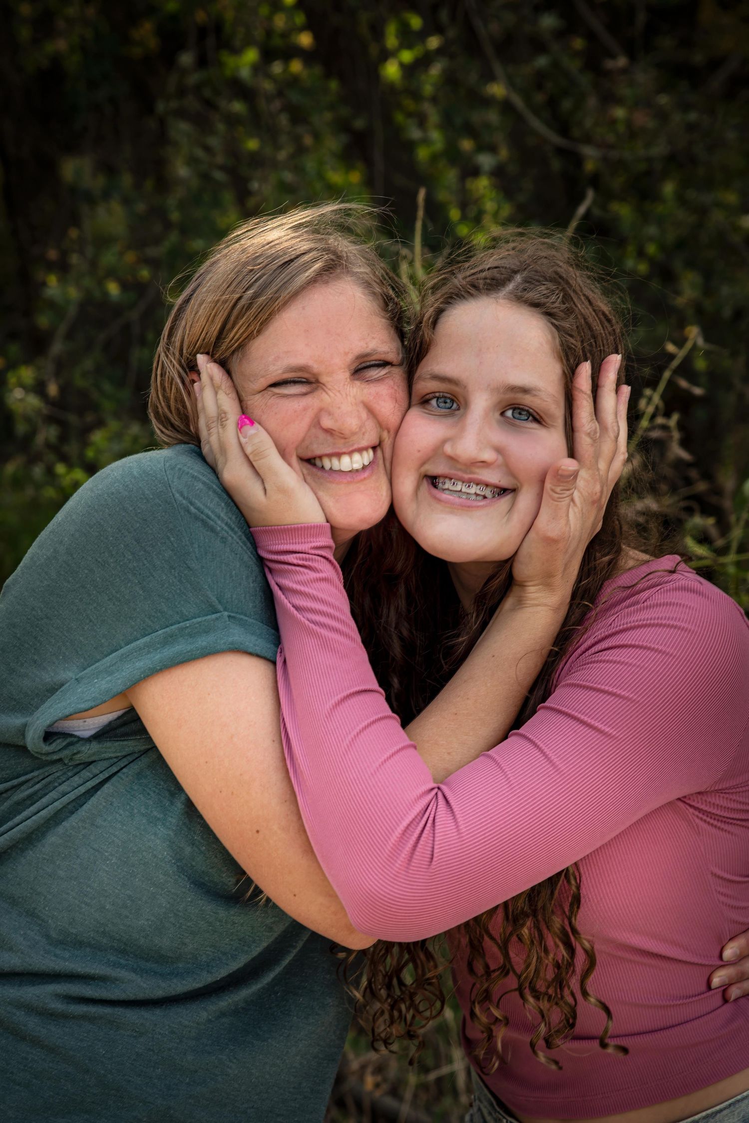 Two happy women laughing and embracing each other outdoors in a warm candid portrait.