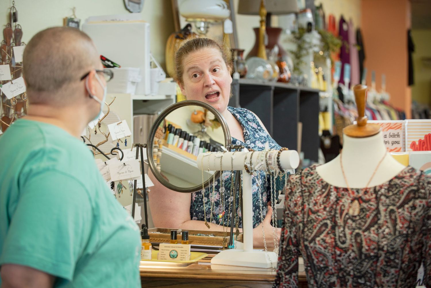 Woman animatedly talking to a customer across a retail shop counter in Bee Balm in Harmony MN.