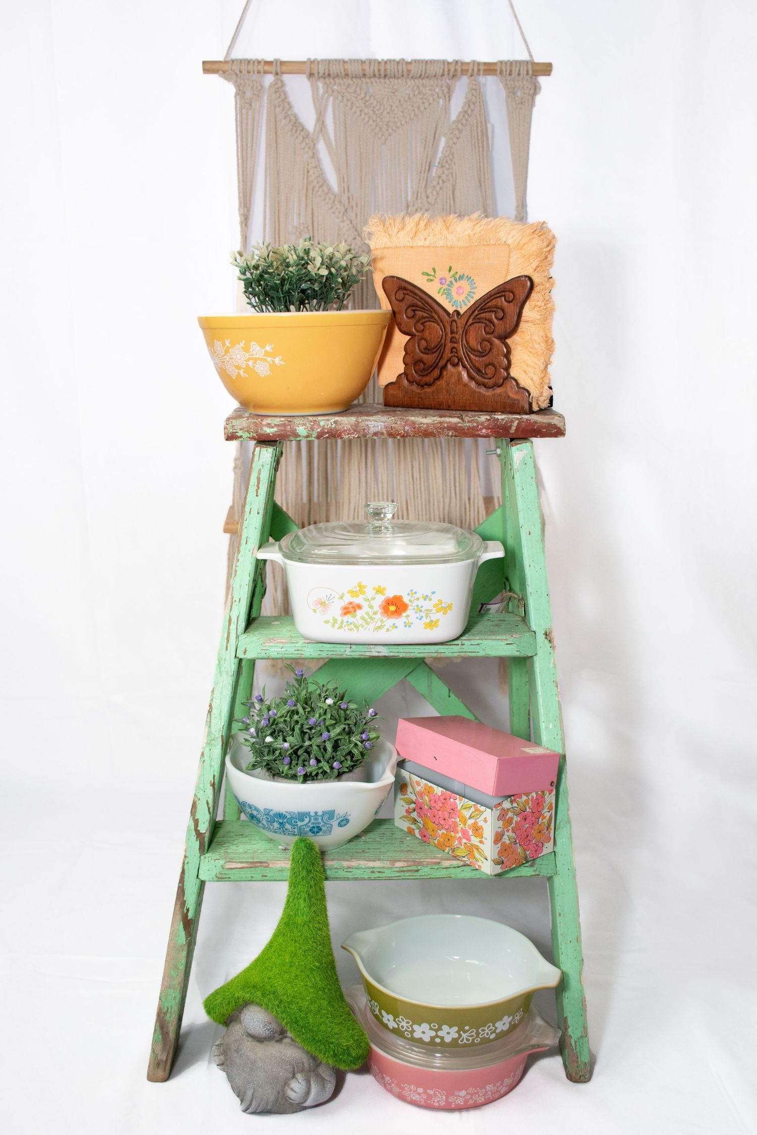 Vintage green ladder shelf styled with Pyrex dishes, plants, and butterfly decor on white background at Bee Balm Boutique.