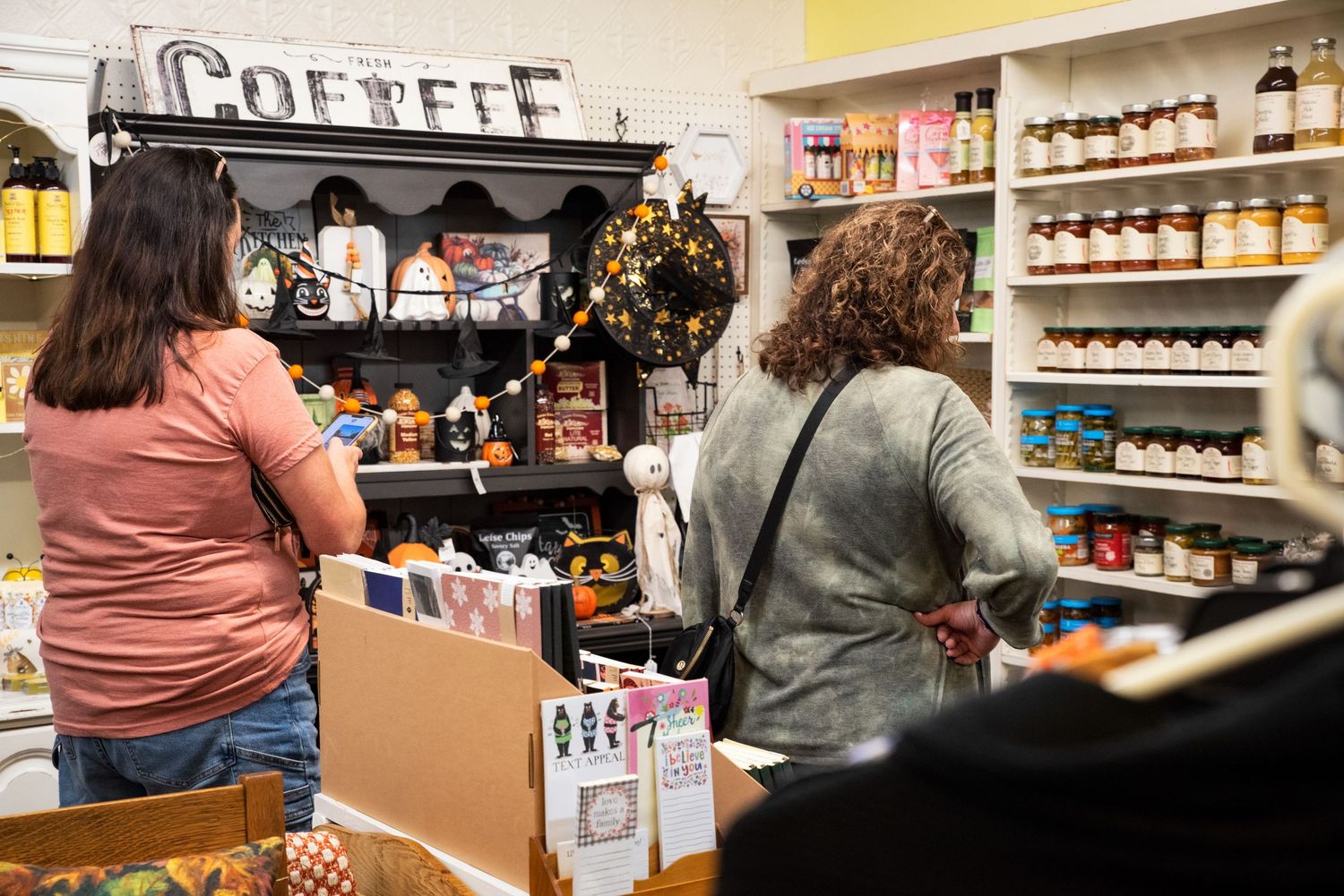 Customers browse shelves of specialty food products and gifts inside a cozy shop at Bee Balm Boutique.