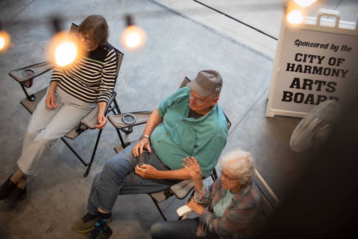 Three seniors relaxing at a City of Harmony Arts Board sponsored outdoor event at Harmony Spirits.