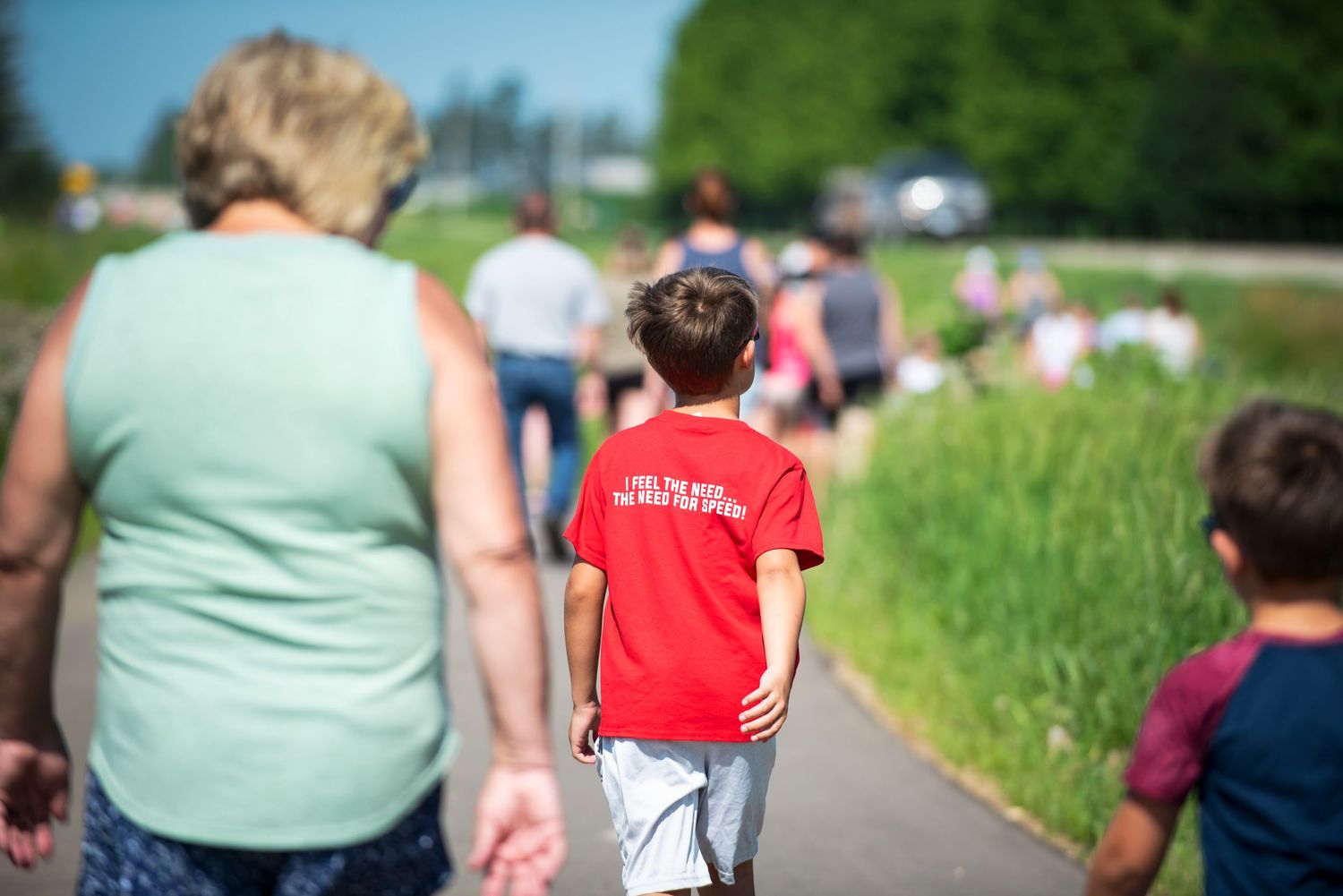Child in red shirt walking on paved path on sunny summer day at Harmony MN 4th of July Celebration..