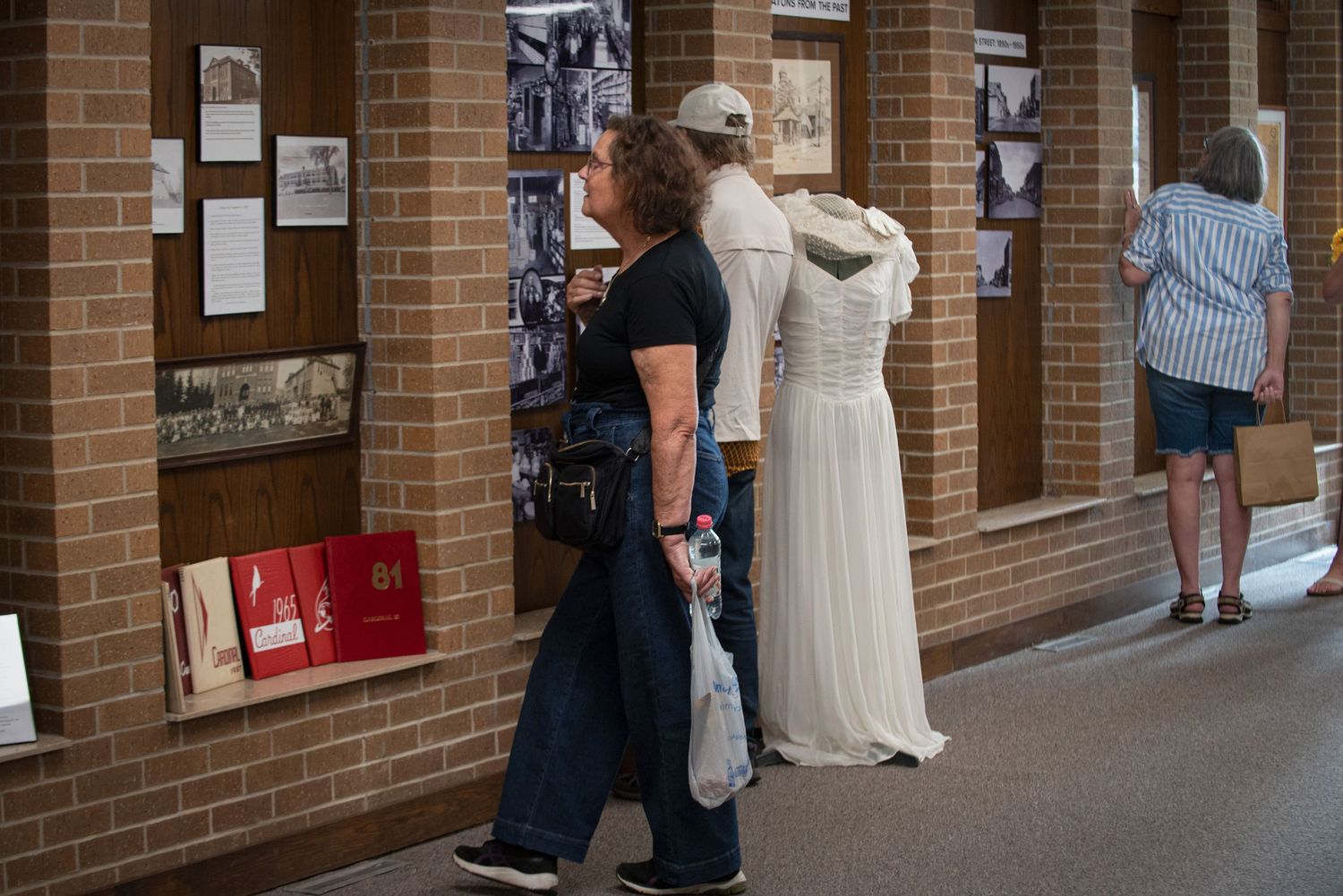 Visitors viewing a historical photo exhibit displayed along a brick hallway wall at the Harmony MN Tourist Center.