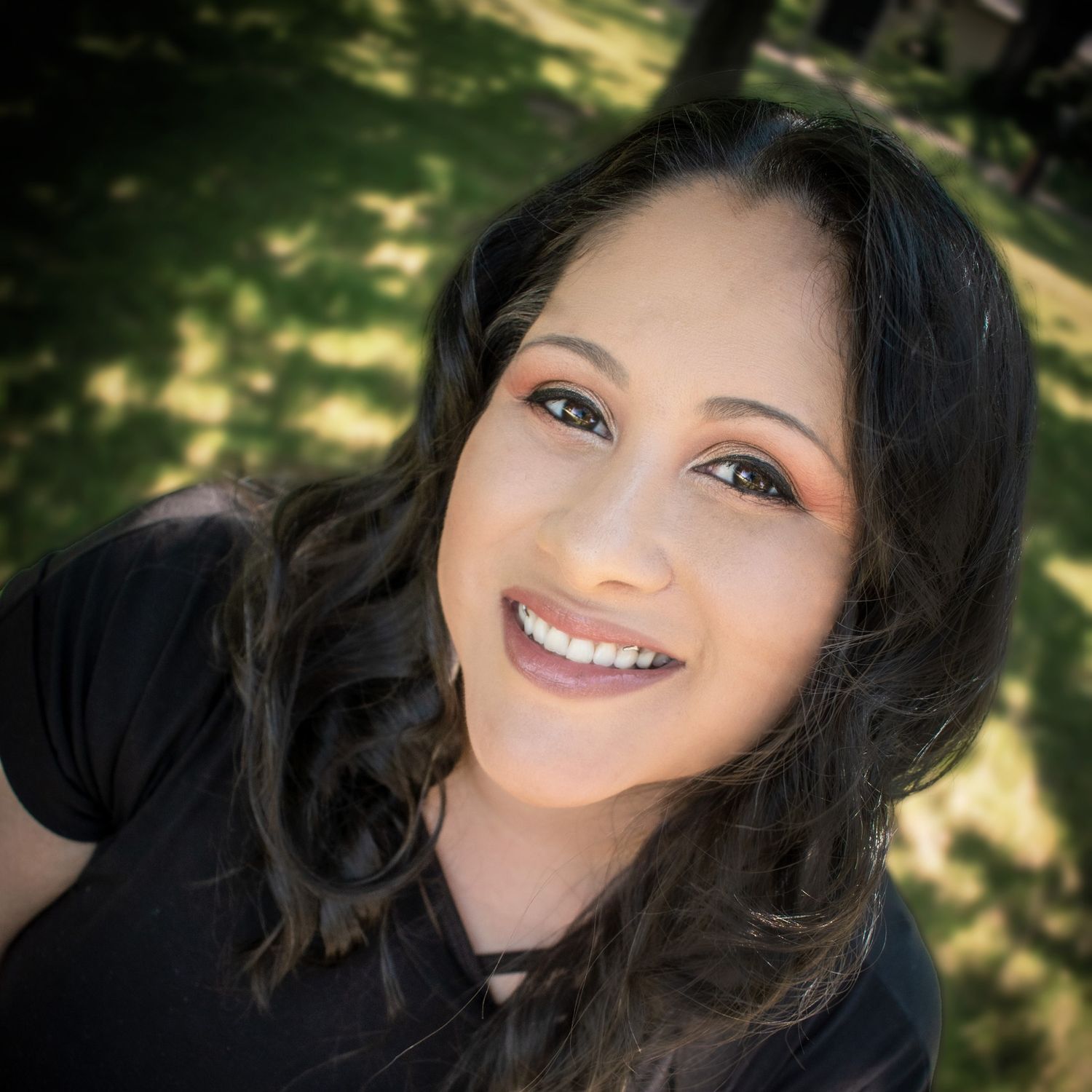 Smiling Hispanic woman with wavy hair photographed from above in a park.