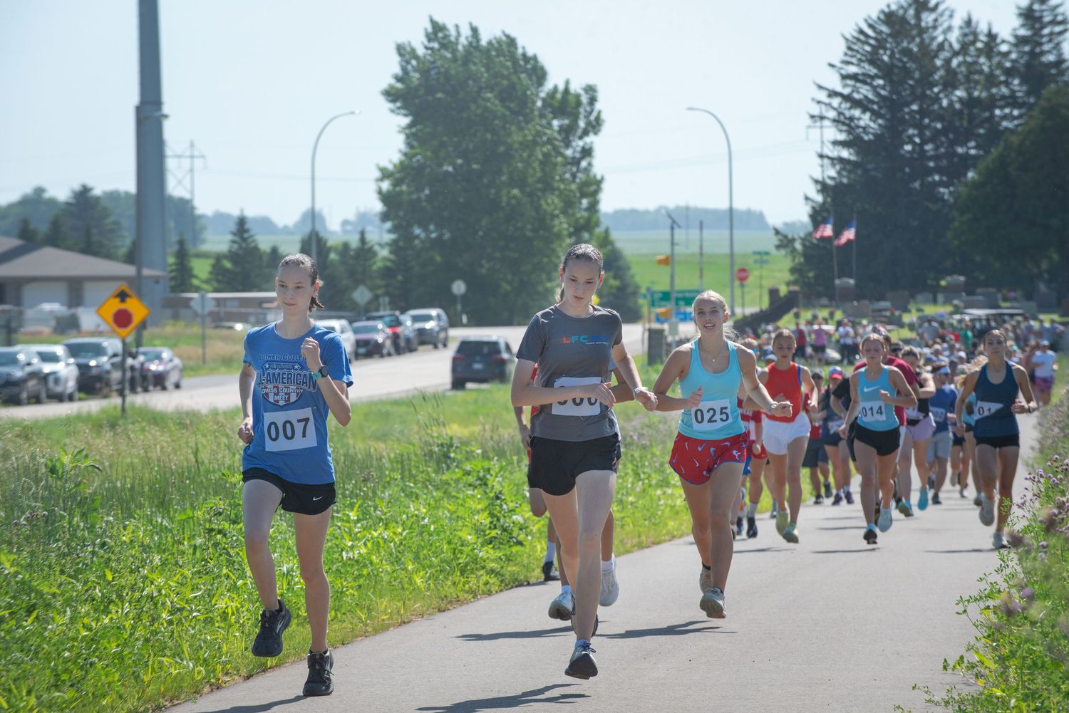 Runners with race bibs competing in outdoor road race on sunny summer day at Harmony MN 4th of July Celebration..