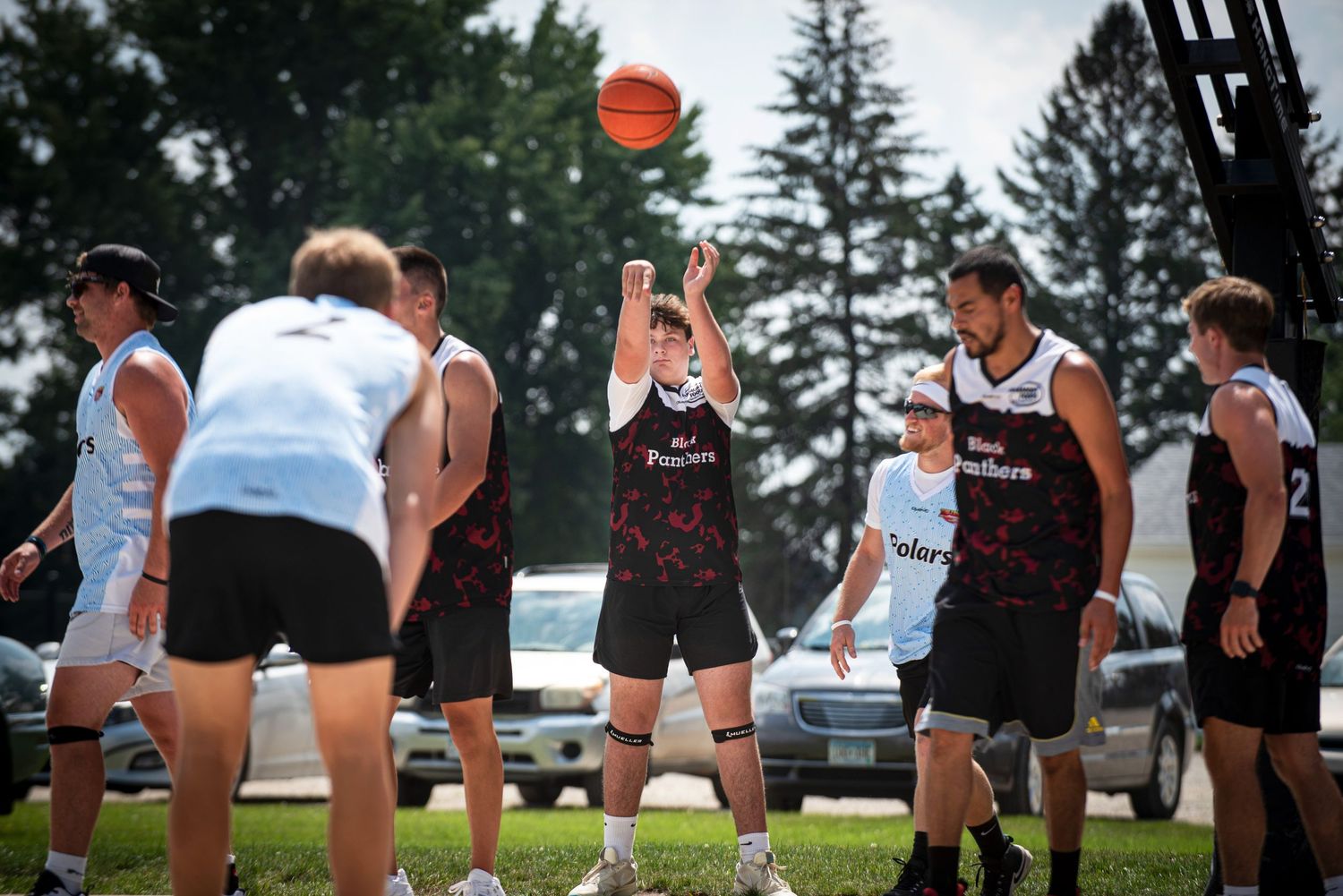 Player shoots free throw as teammates and opponents watch during outdoor Rucker League basketball game.